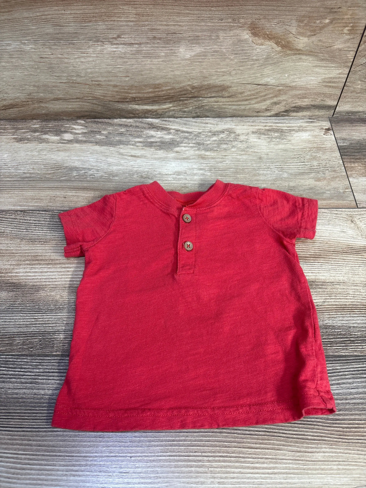 Red Just One You baby henley shirt for 12 month old on a wood floor