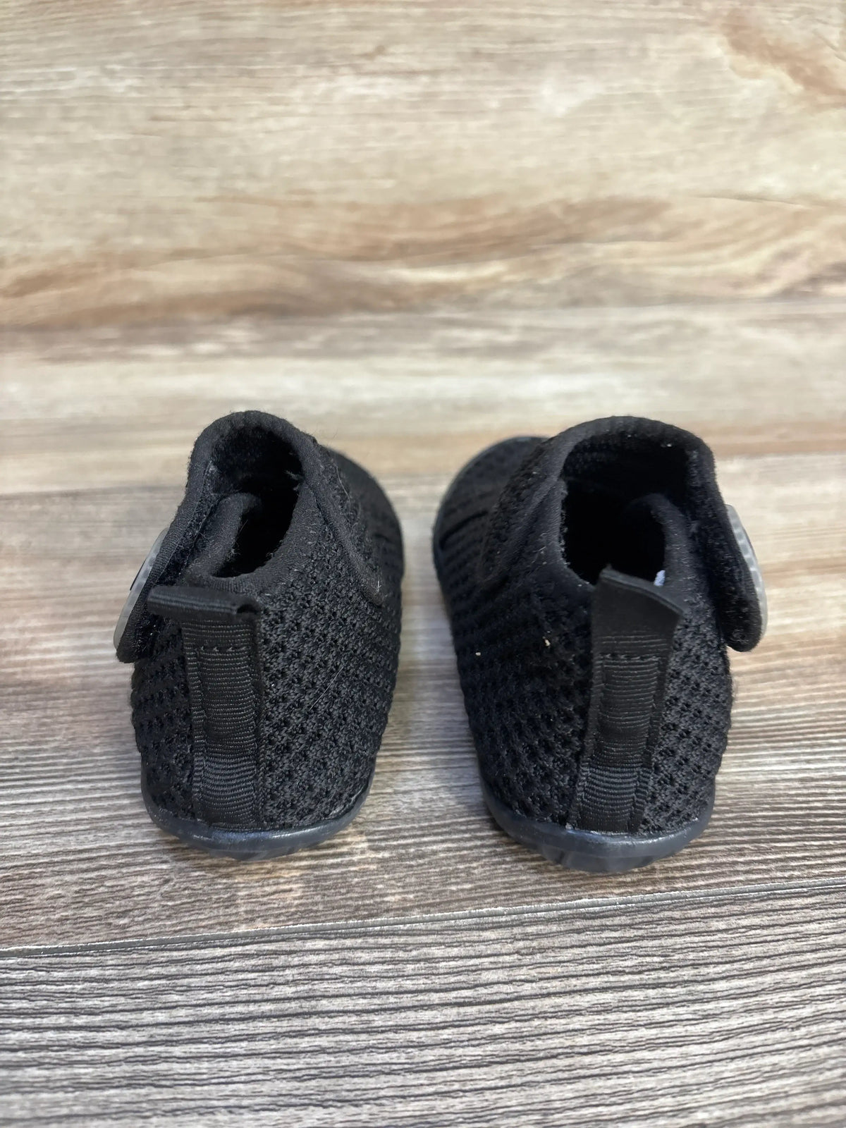 Rear view of black FEETCITY high-top mesh sock shoes for kids on a wooden surface.