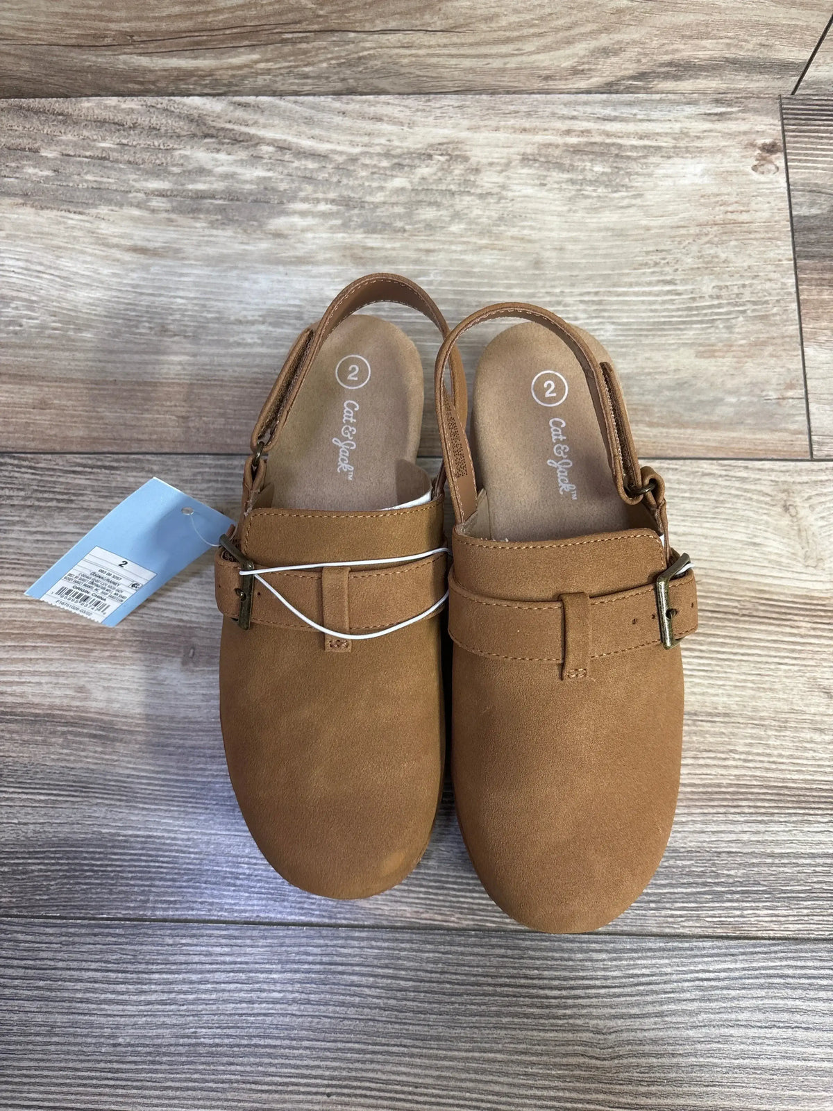 Pair of brown toddler clogs with buckle straps size 2 by Cat & Jack on wooden floor