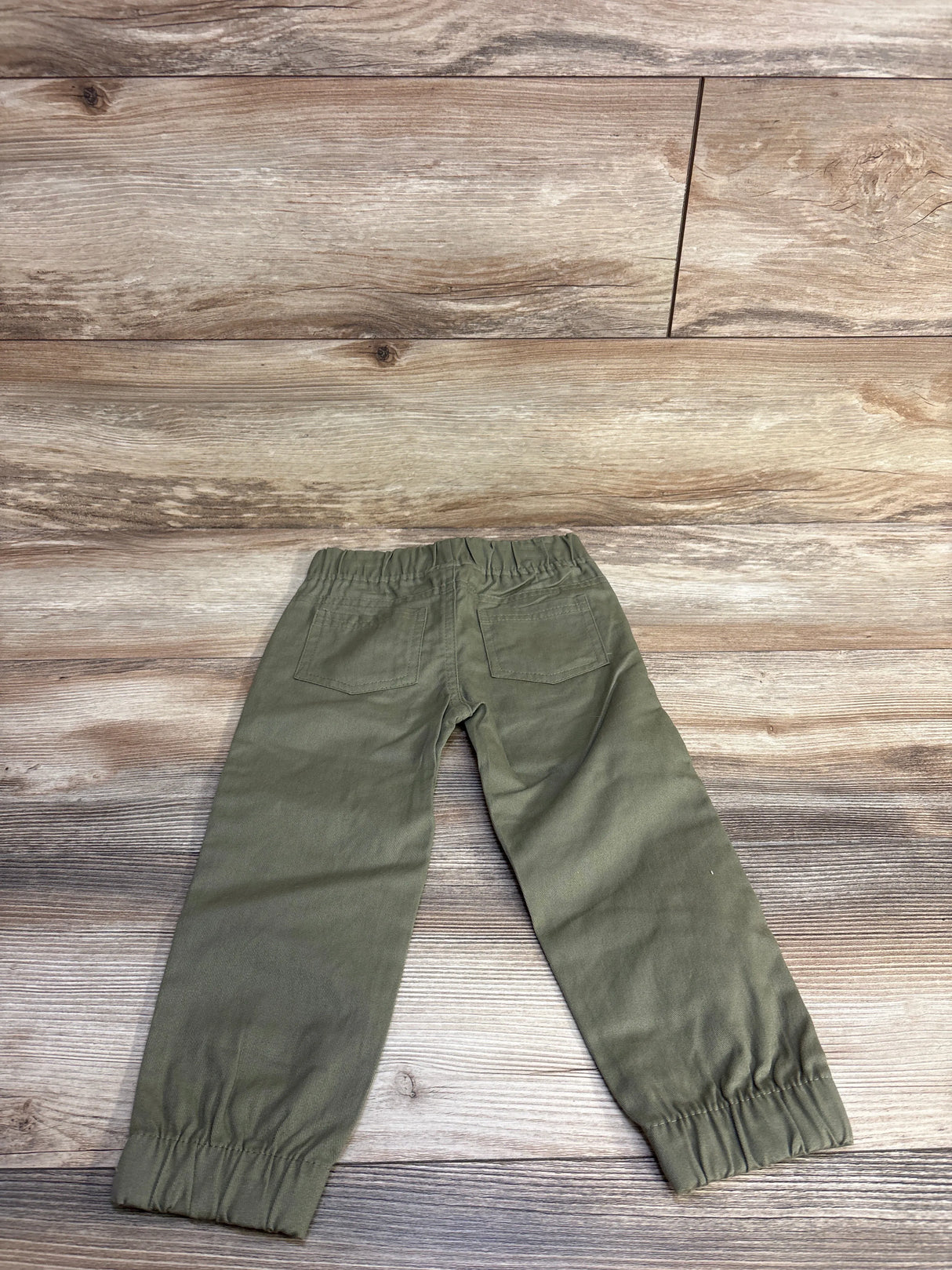 Back view of green toddler pull-on pants 3T showcasing elastic waistband and gathered ankle cuffs on wood floor