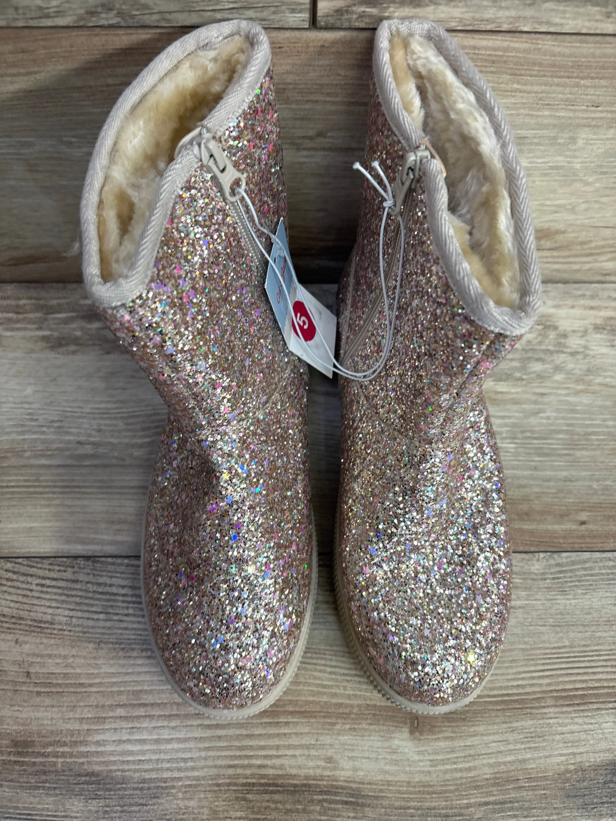 Sparkly glitter pink toddler boots with faux fur lining on a wooden floor