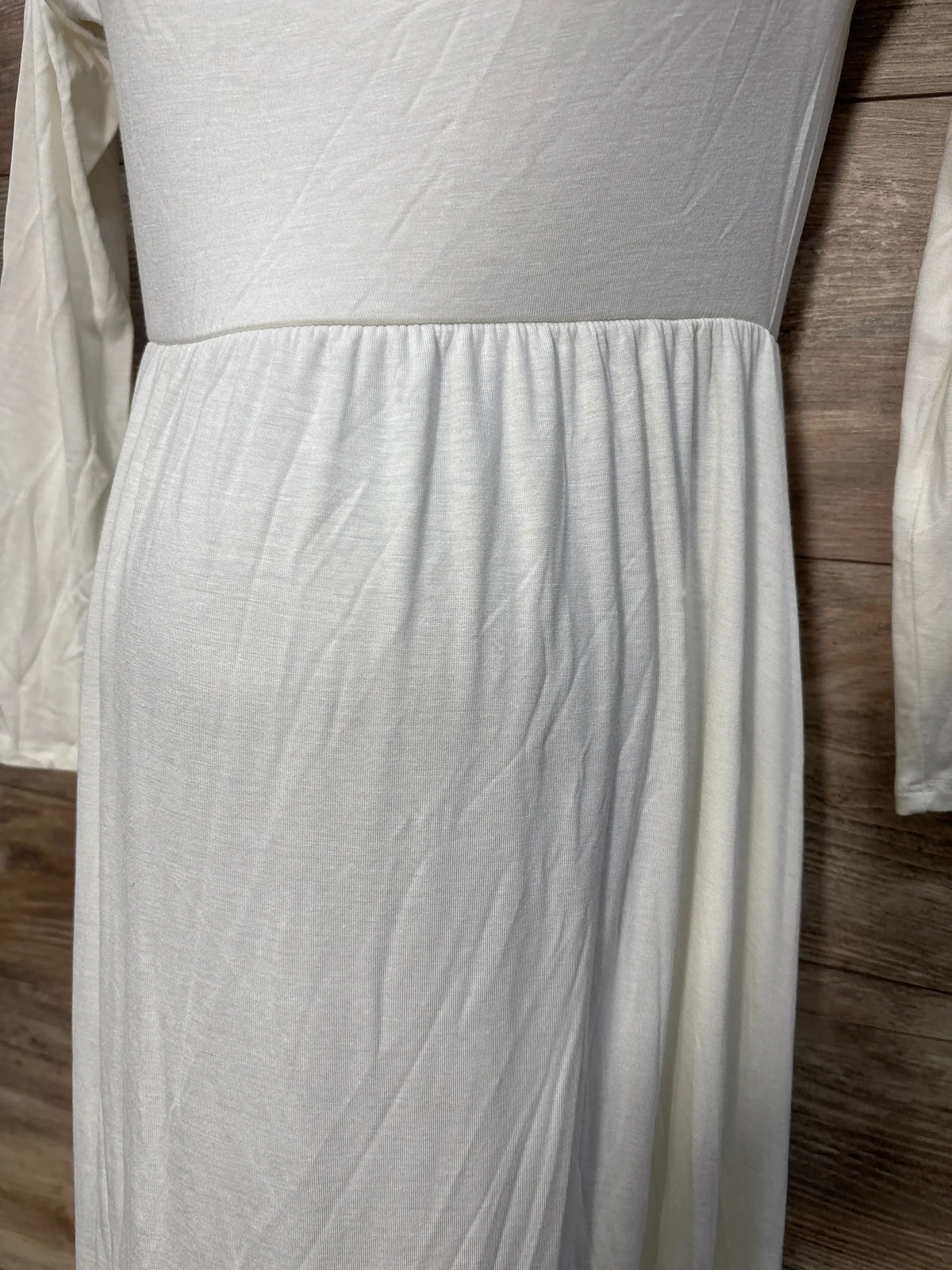 White long sleeve maternity dress with gathered waist, displayed on wood background
