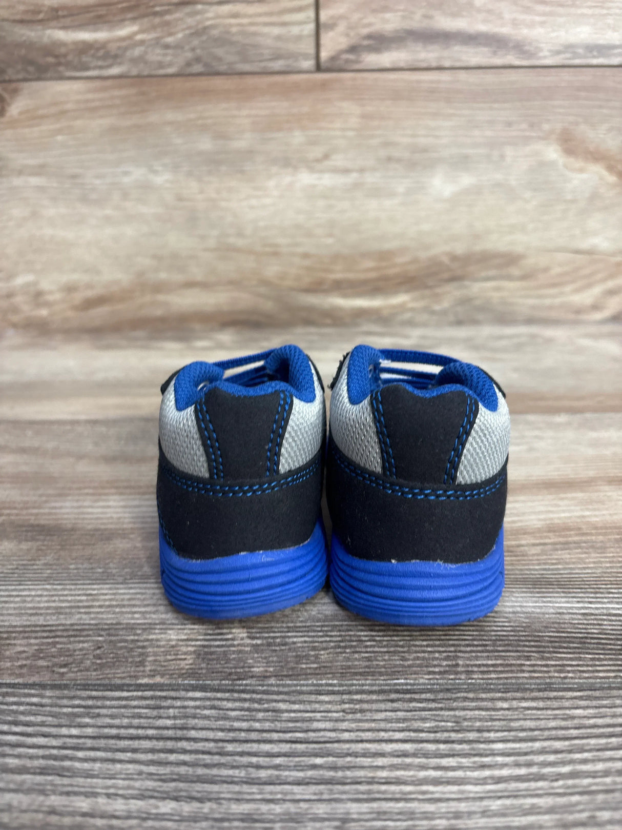 Back view of blue and gray toddler sneakers on wooden floor