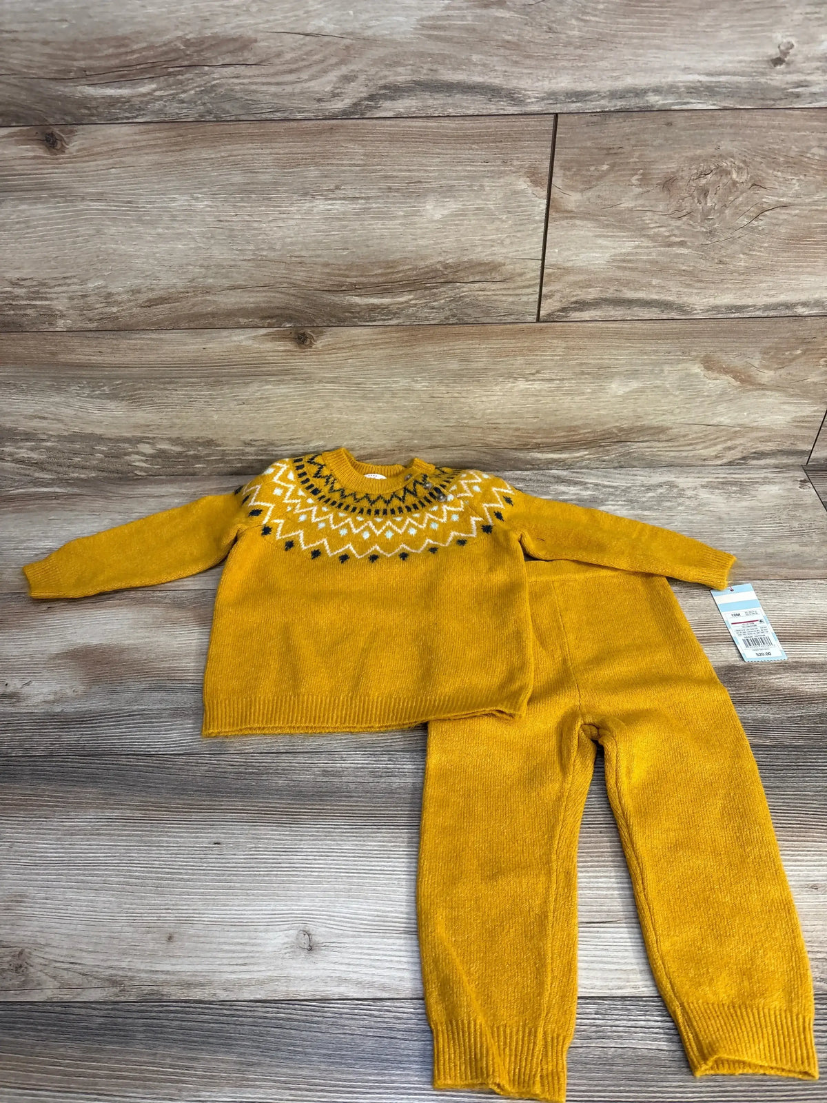 Yellow knit kids sweater and pants set with geometric pattern, laid on wooden floor