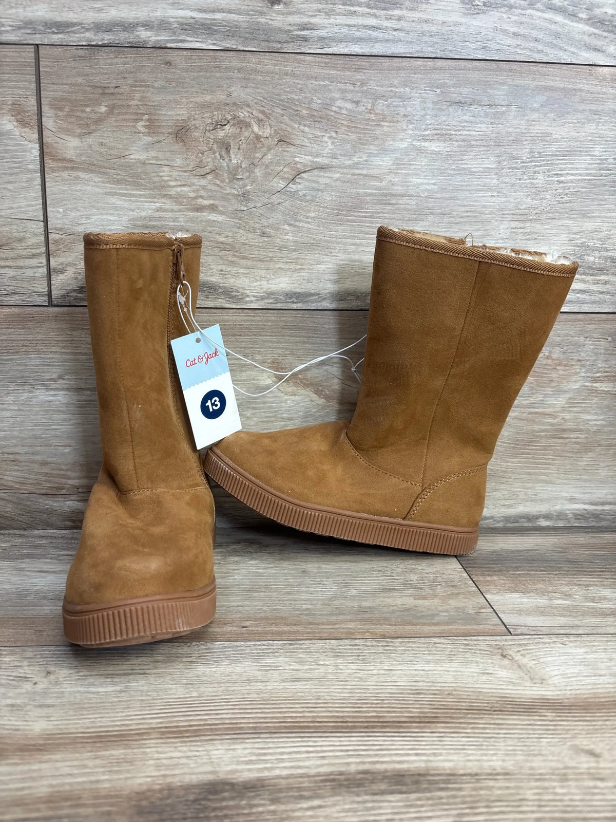 Pair of tan suede kids boots with rubber soles, size 13, on wood floor