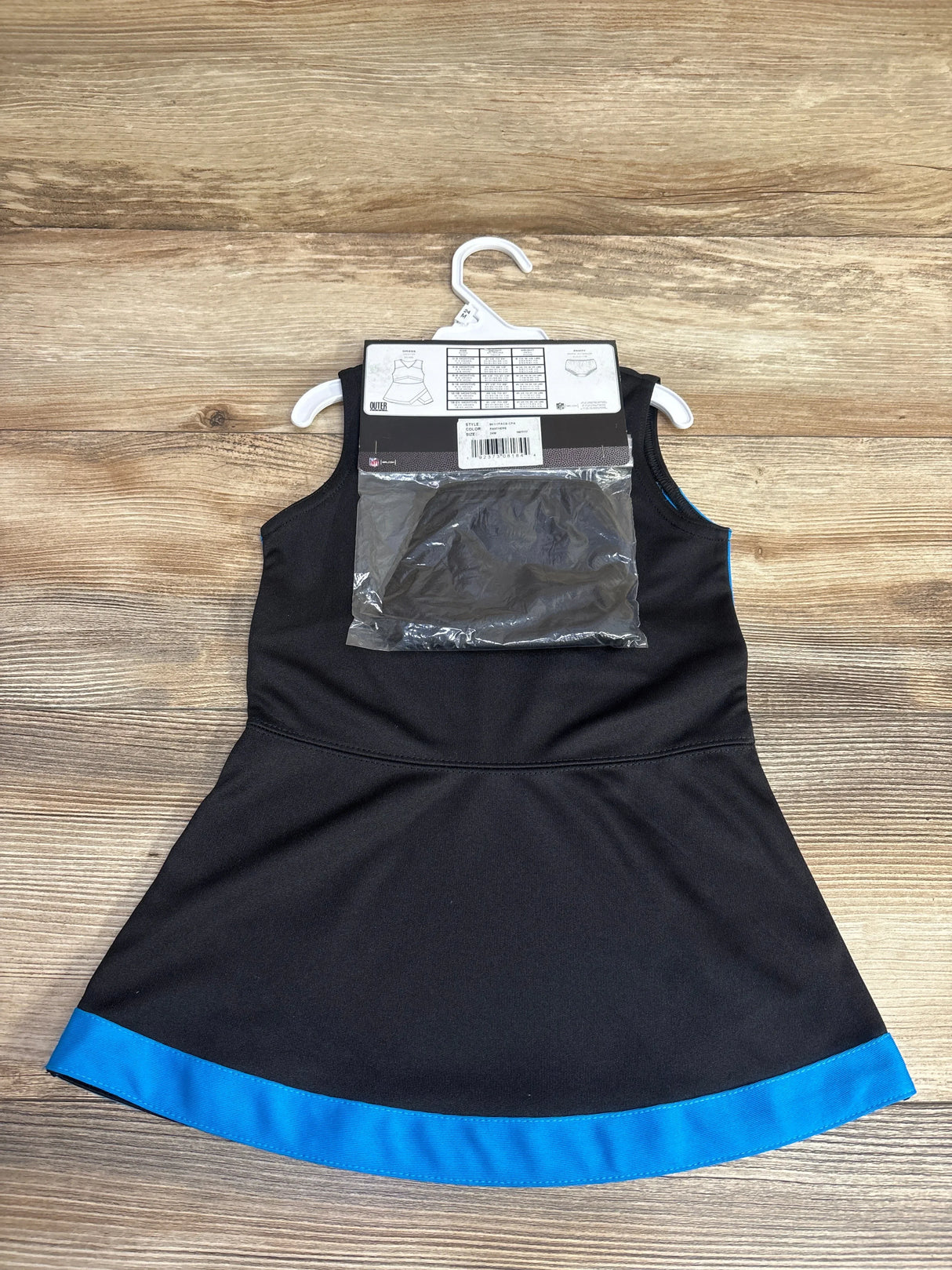 Front view of Carolina Panthers 2-piece cheer jumper dress 24M with team logo and matching sports bra on wooden floor