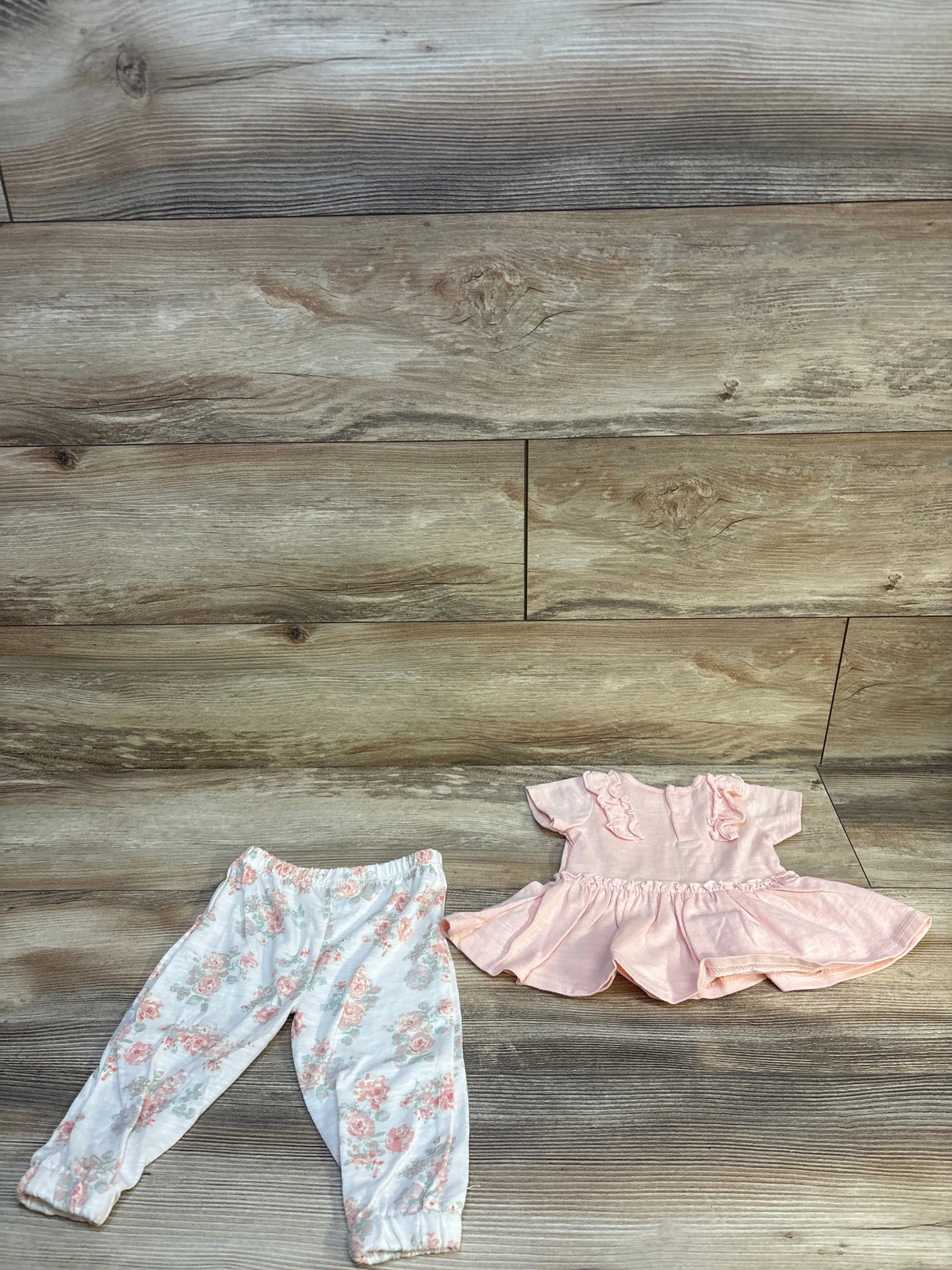 Infant girl floral pants and ruffled pink short sleeve dress outfit on wooden background
