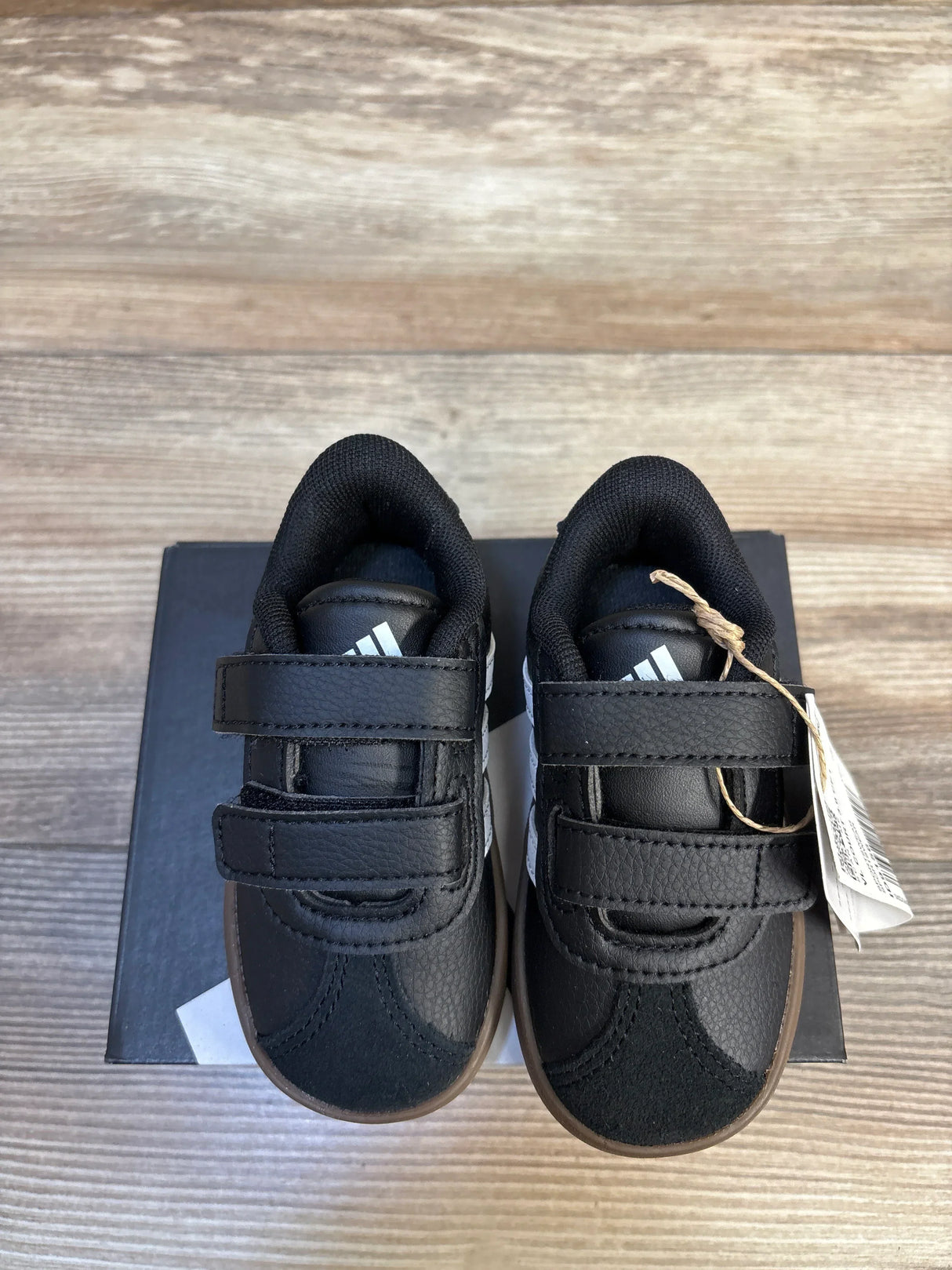 Black Adidas toddler sneakers with velcro straps, resale kids shoes on wooden surface