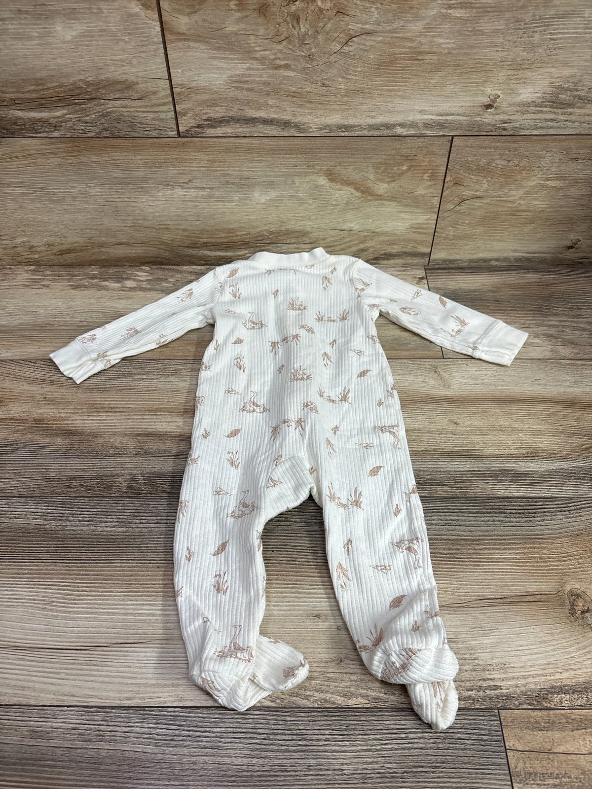 Carter's ivory ribbed baby sleeper with a brown nature print on a wooden background