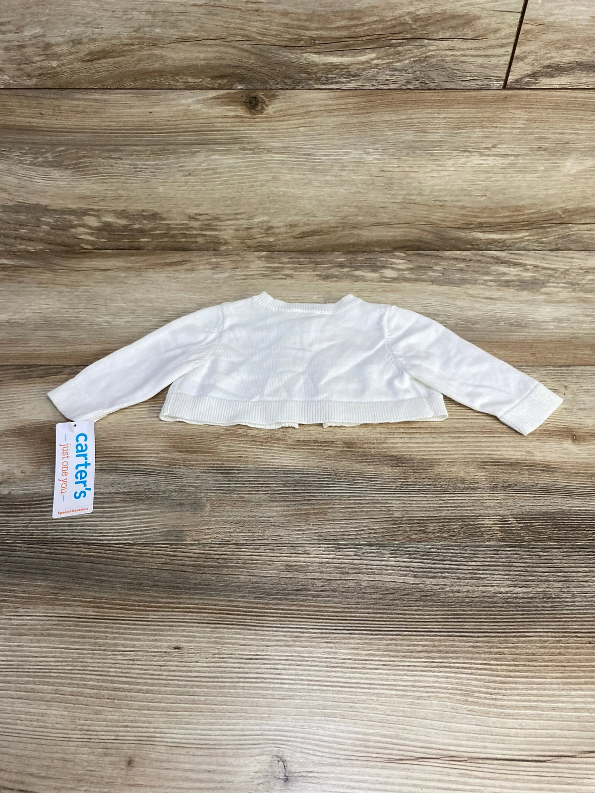 Front view of newborn white cardigan showcasing front opening and long sleeves on plain white background