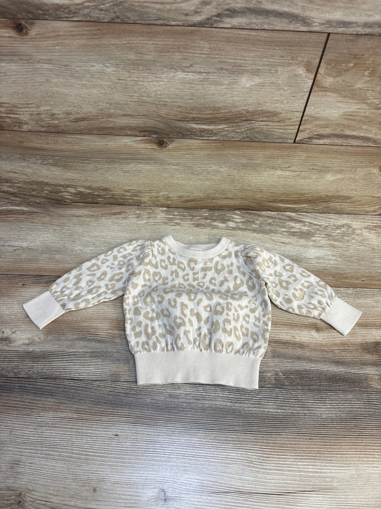 Cream leopard print kids sweater on wood floor, cozy long sleeve top for toddlers