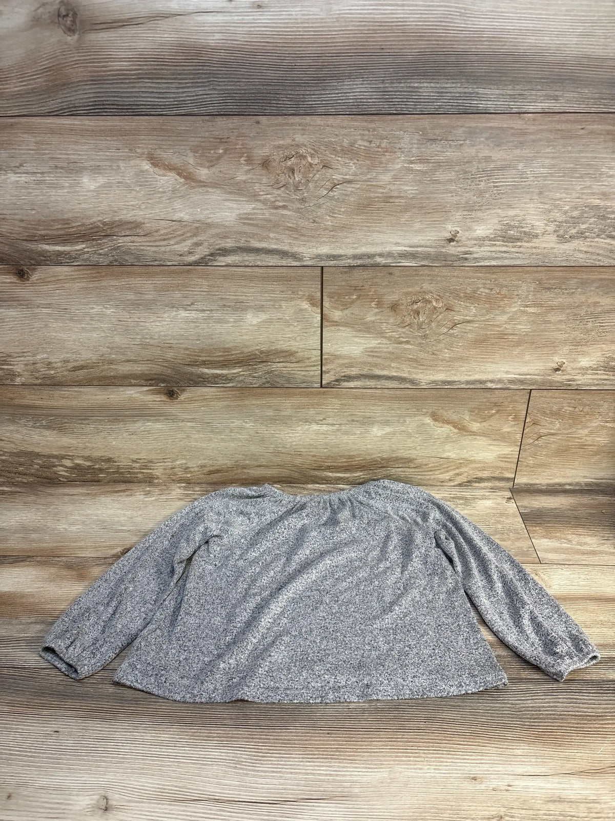 Gray long sleeve kids shirt laid flat on wood floor, ideal for resale clothing