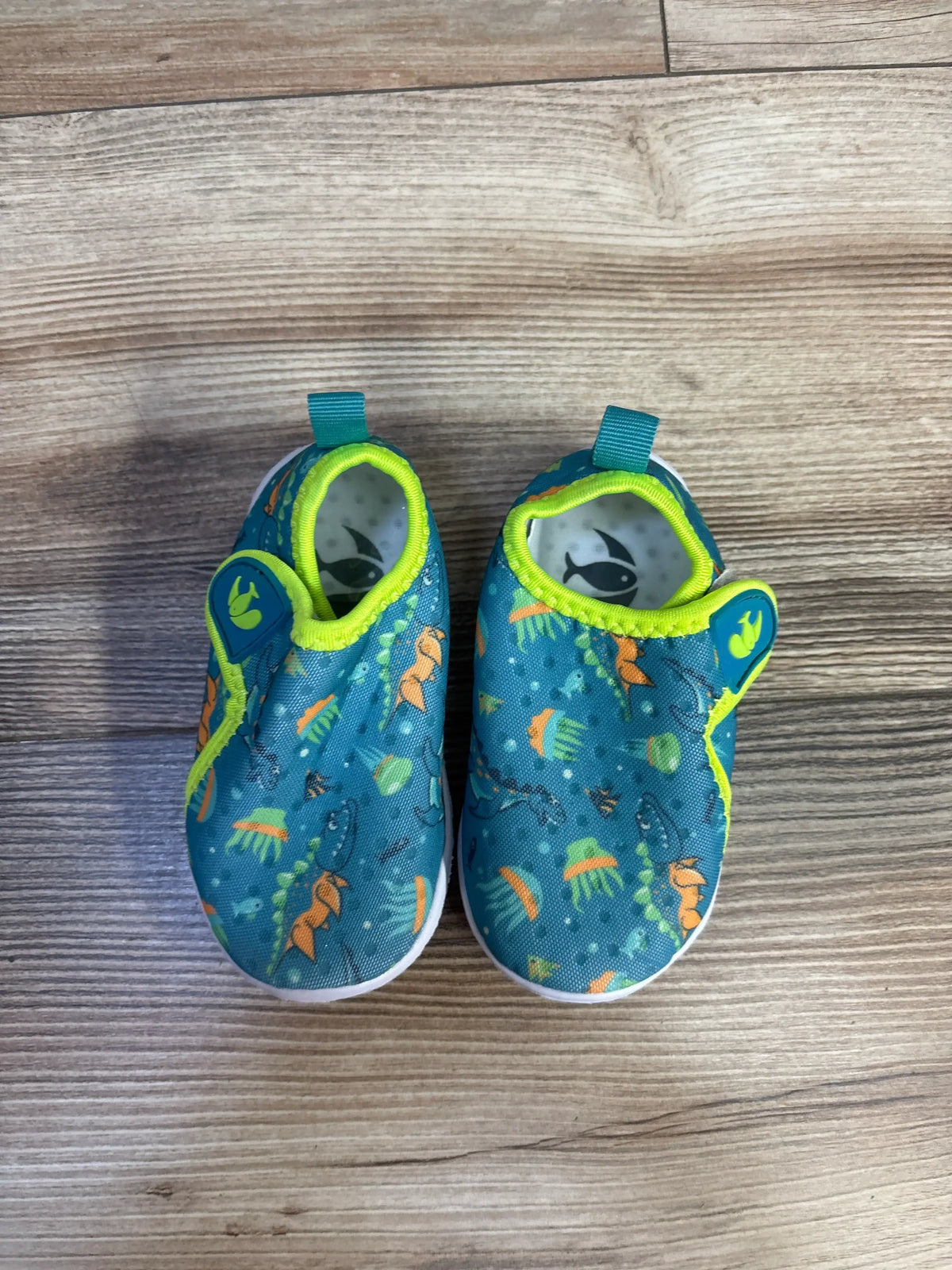 Top view of FEETCITY wide barefoot water shoes showcasing teal aquatic print and lime trim on a wood floor