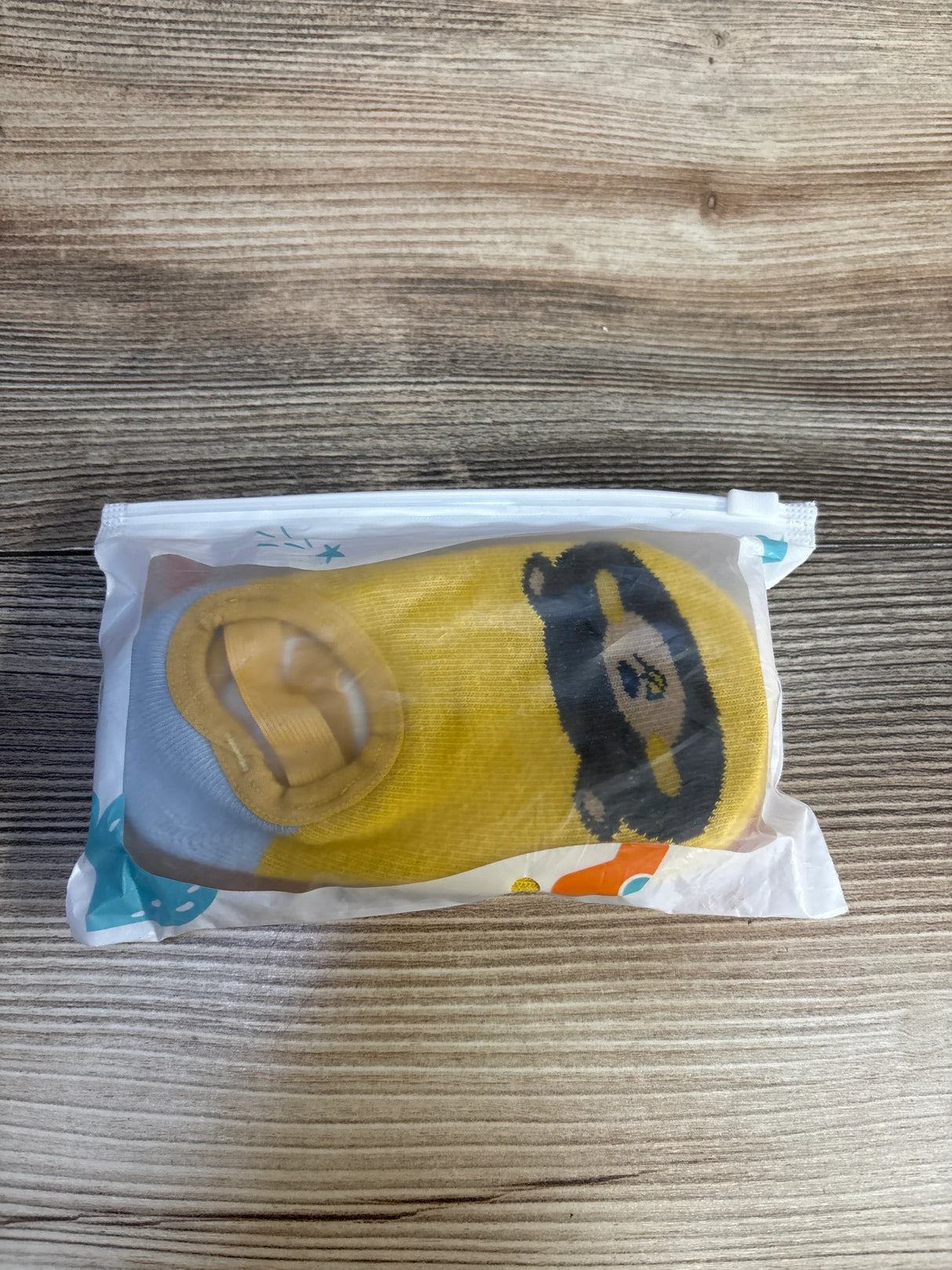 Yellow baby sock with bear design, packaged for resale, ideal for kids and maternity shopping.