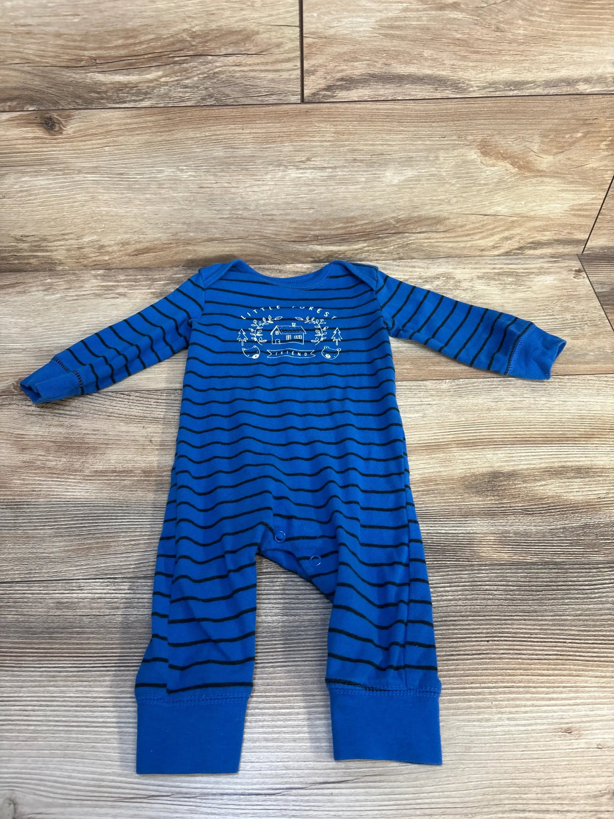 Blue striped baby sleeper with forest graphic, long sleeves, on wood floor