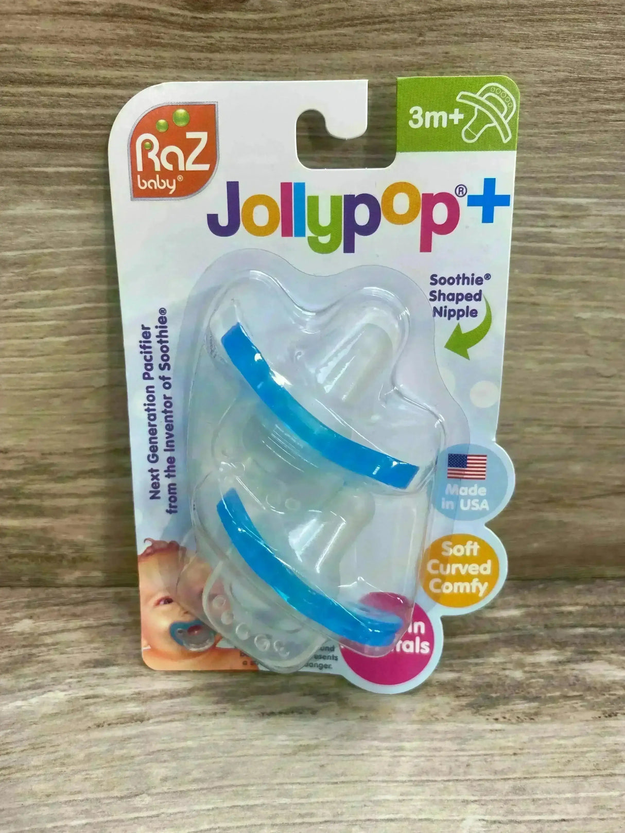 Front view of Raz Baby JollyPop 2-pack pacifiers showing translucent shields with blue trim and silicone nipples on wood