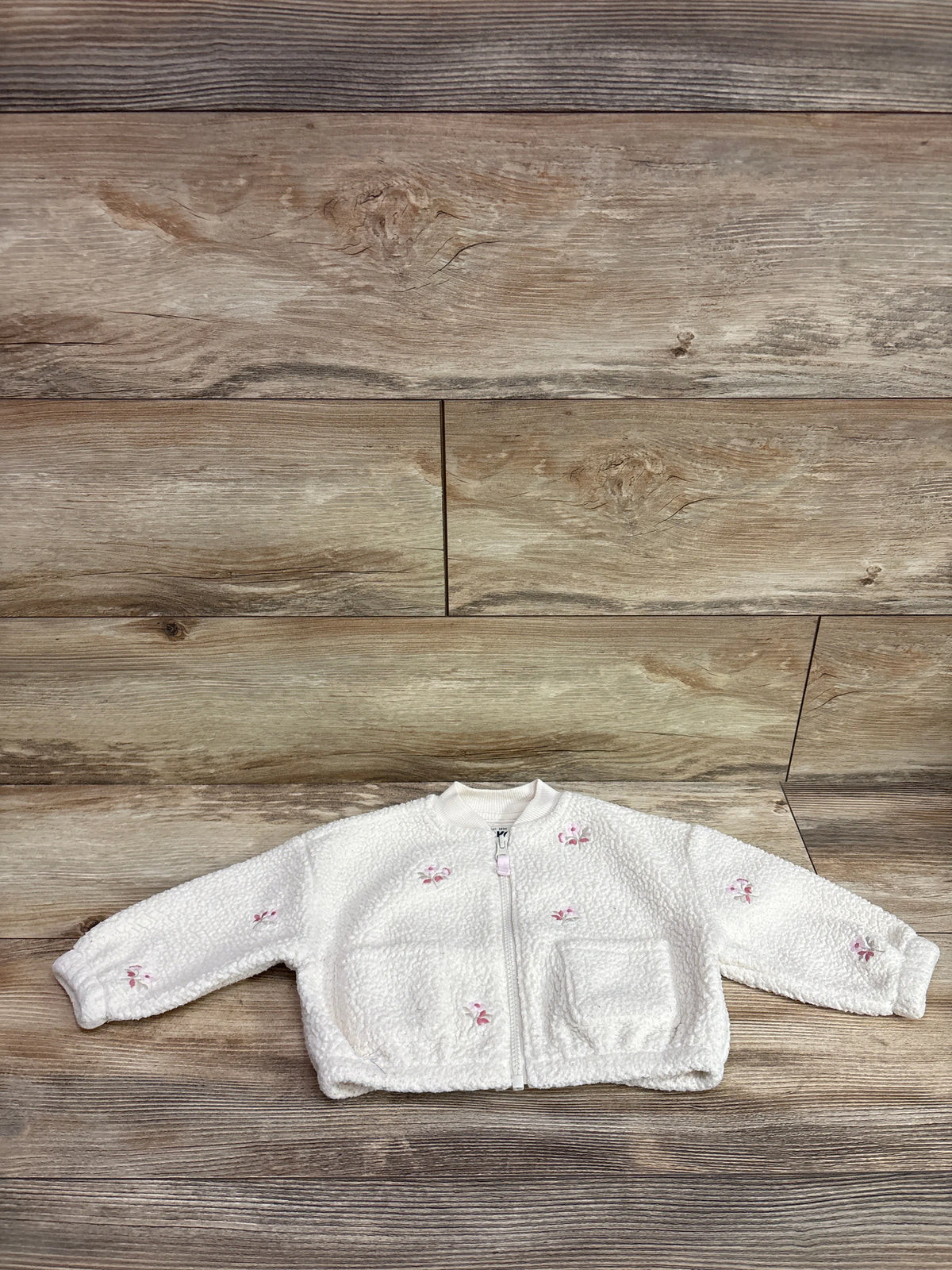 Ivory Oshkosh embroidered sherpa jacket for infants on a rustic wood background