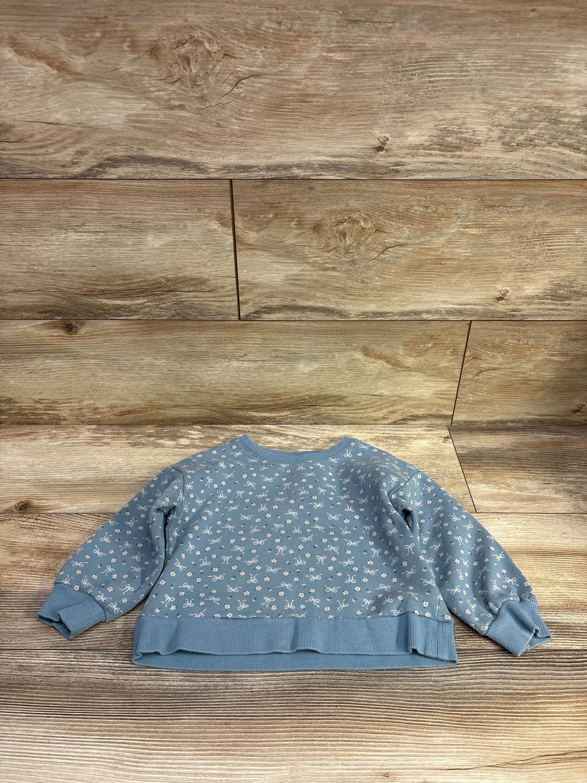 Front view of Carter’s blue pullover sweatshirt in size 3T showcasing a white bow print and ribbed cuffs and hem