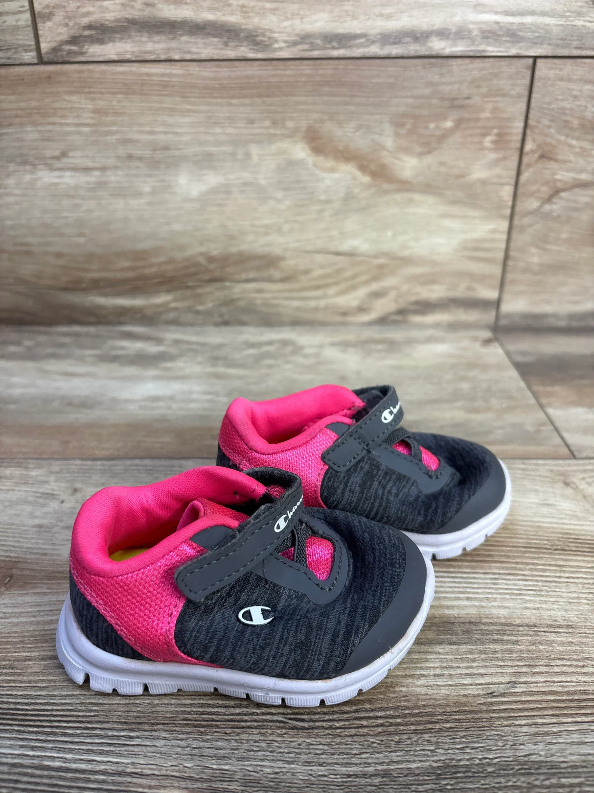 Front-three-quarter view of Champion toddler sneakers size 3C showing grey upper, pink lining, Velcro strap on wood floor