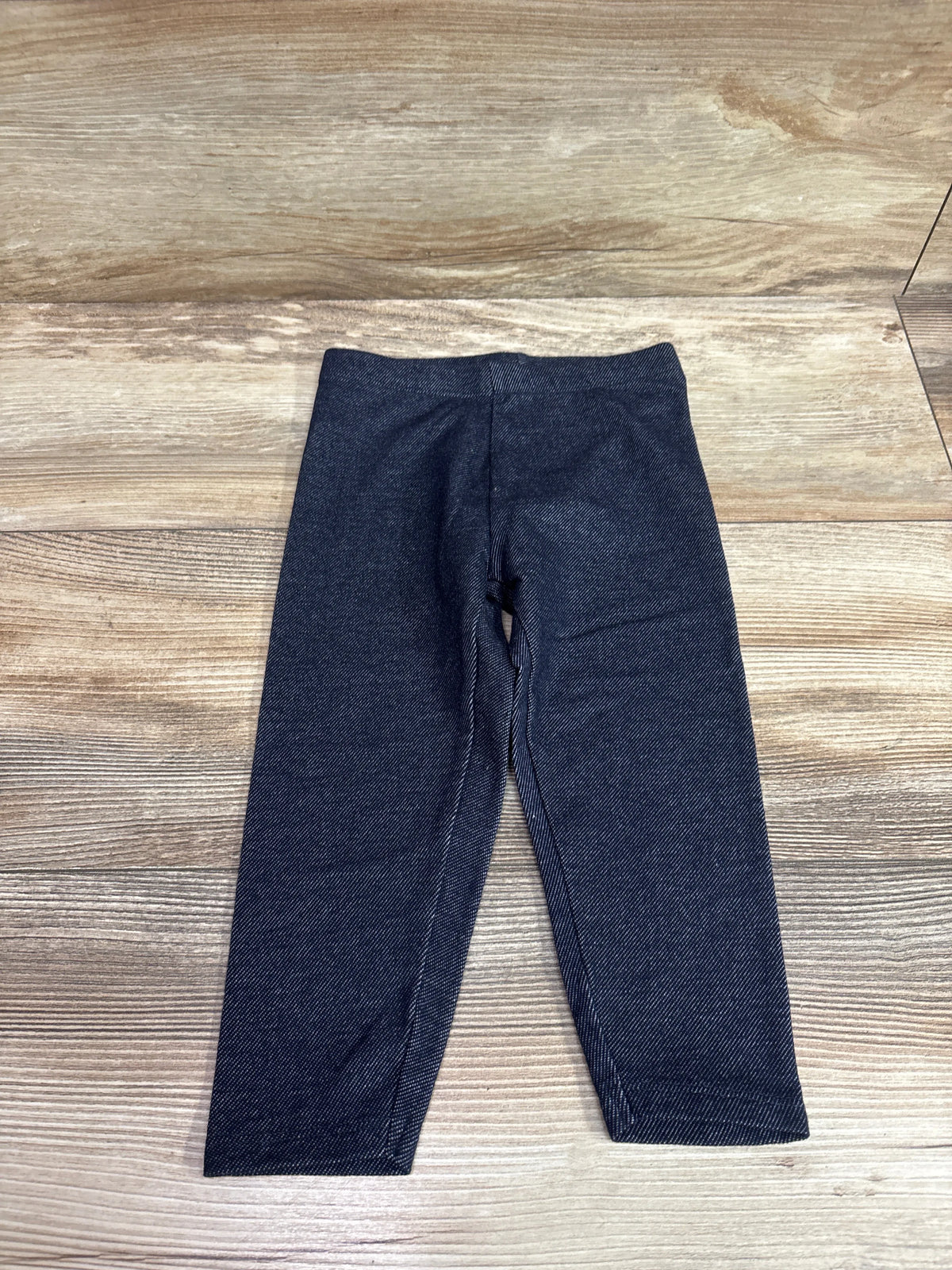 Front view of Cat & Jack navy leggings in size 2T showing an elastic waistband on a wood floor