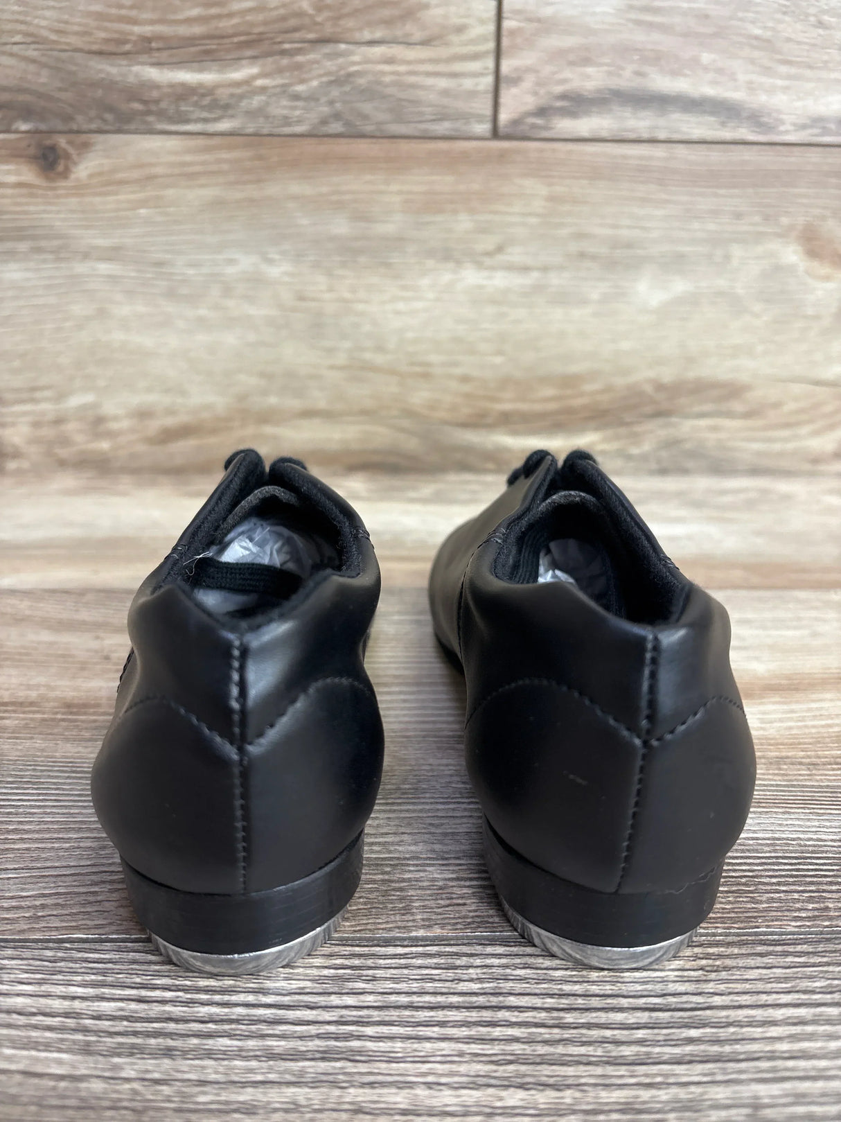 Pair of black leather tap dance shoes for kids on wooden floor background