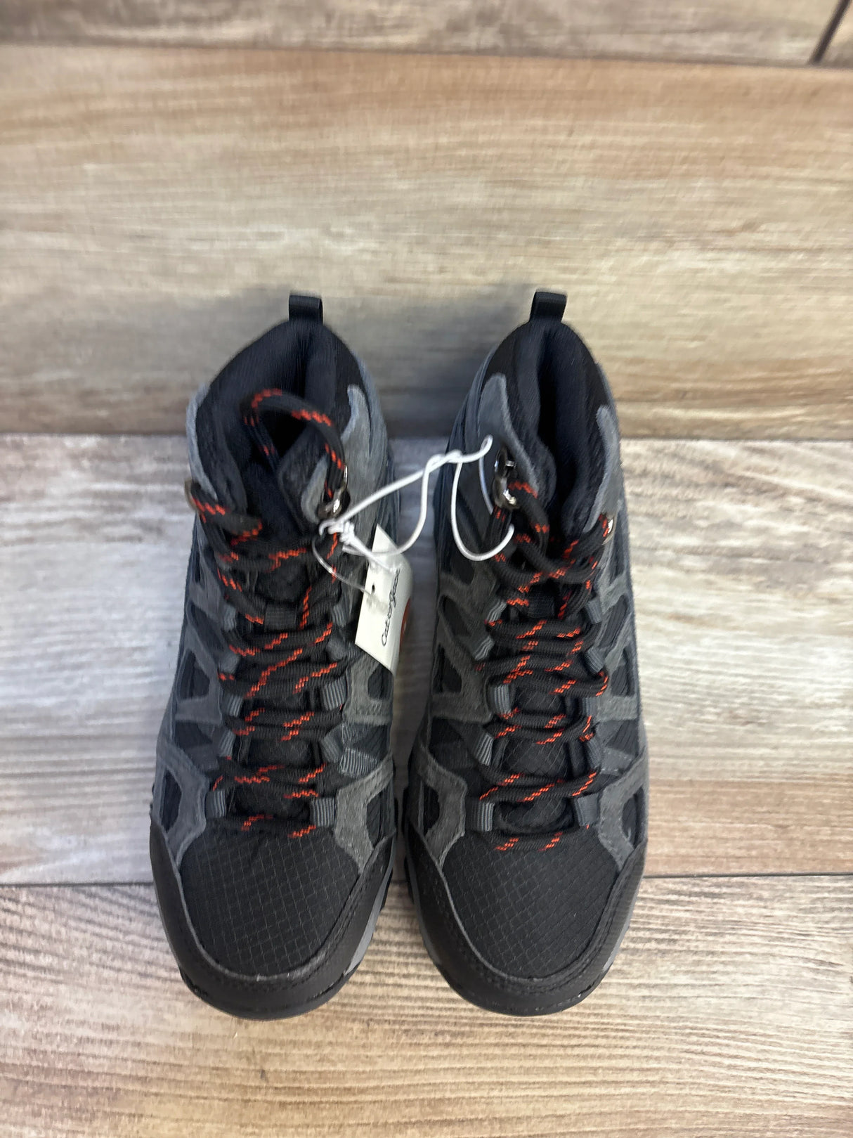 Kids black and gray athletic sneakers with red laces on wood background