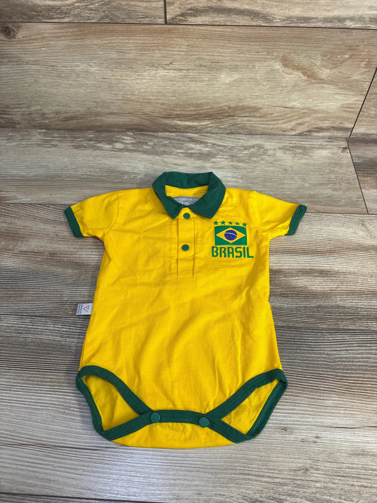 Front view of yellow Revedor Brazil polo bodysuit with green trim, Brazil graphic, button front, and leg snaps on wood floor