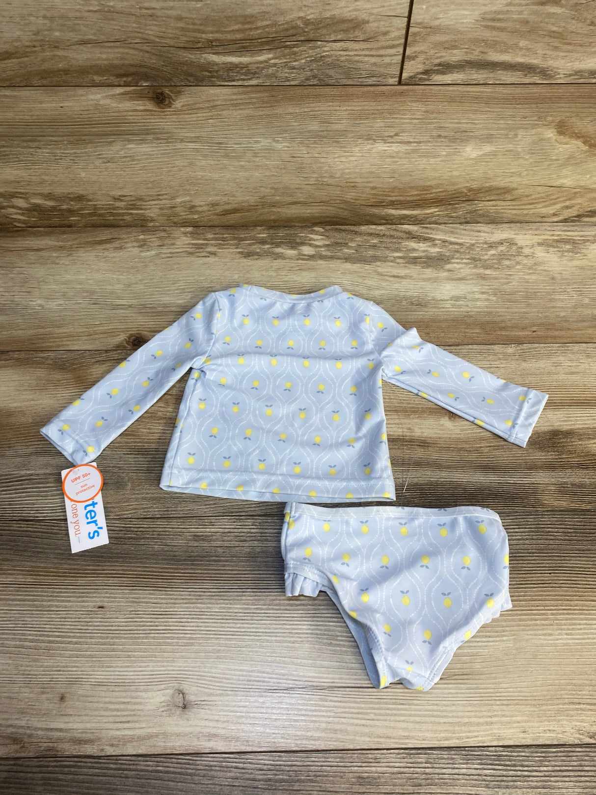 Long sleeve baby swim set with yellow print, sun protection, laid on wood floor