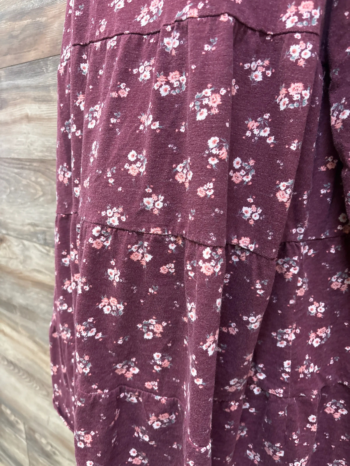 Close-up of a maroon tiered maternity dress with a small white and pink floral print.