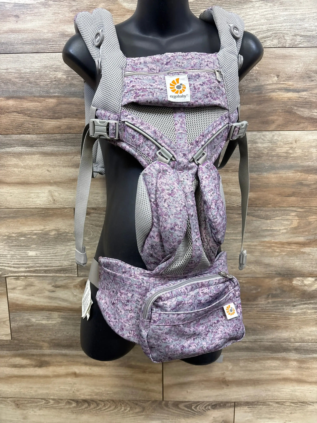 Purple patterned Ergobaby baby carrier with mesh panels displayed on mannequin