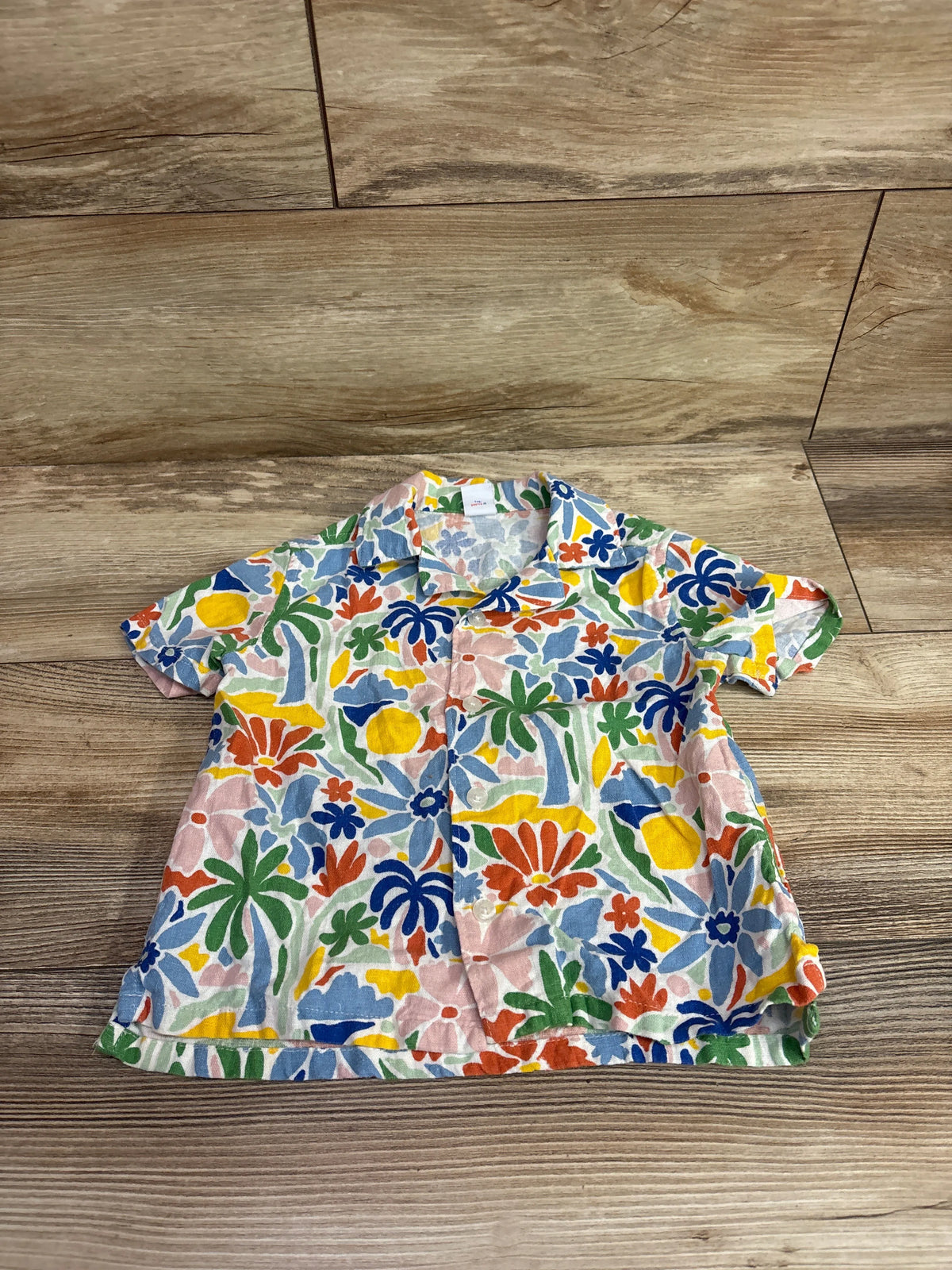 Front view of Old Navy linen blend button-up shirt in size 2T showcasing a colorful floral pattern on a wood floor