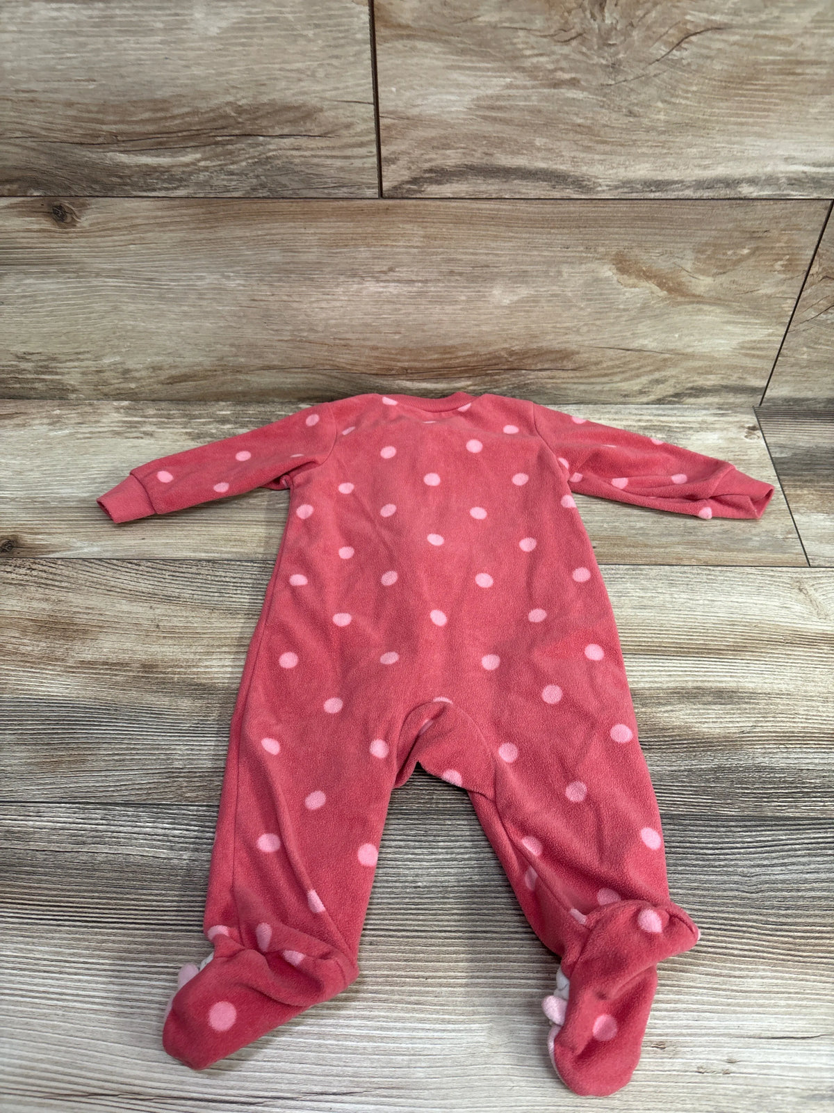 Flat lay of a pink Just One You blanket sleeper with light pink polka dots and covered feet on a wood background