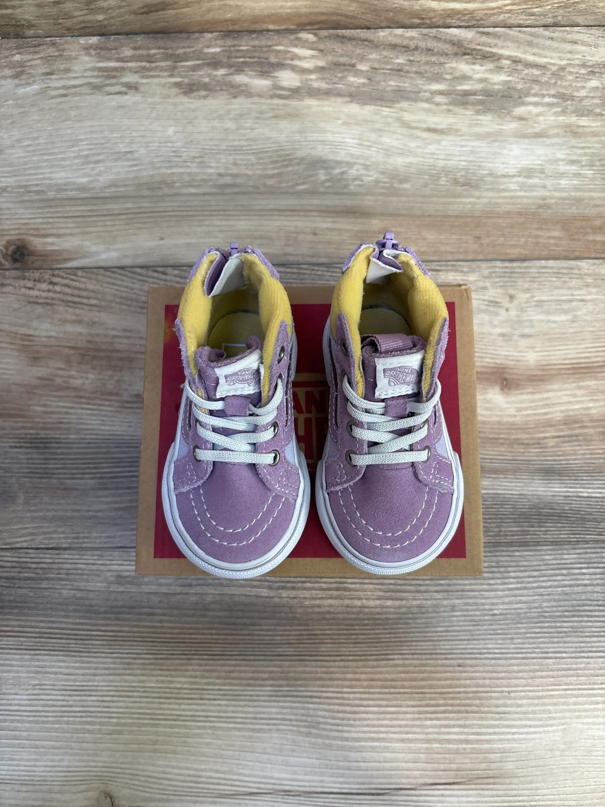 Top view of purple Vans MTE Sk8 Hi-Zip toddler sneakers showing white laces, yellow lining, and rear zippers on wood