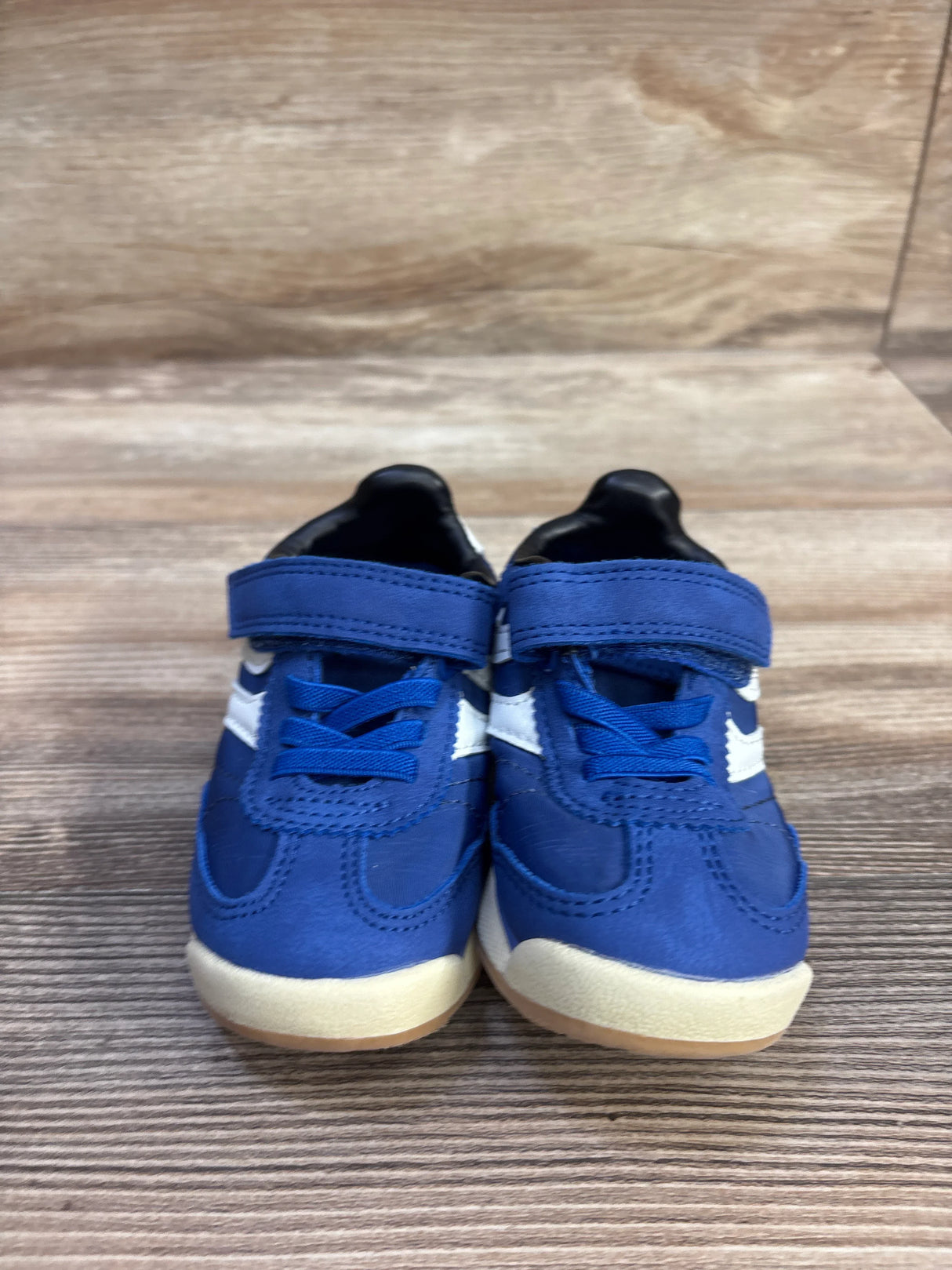 Front view of blue Wonder Nation toddler sneakers, size 6C, with Velcro strap, elastic laces and white side star on wood-grain surface