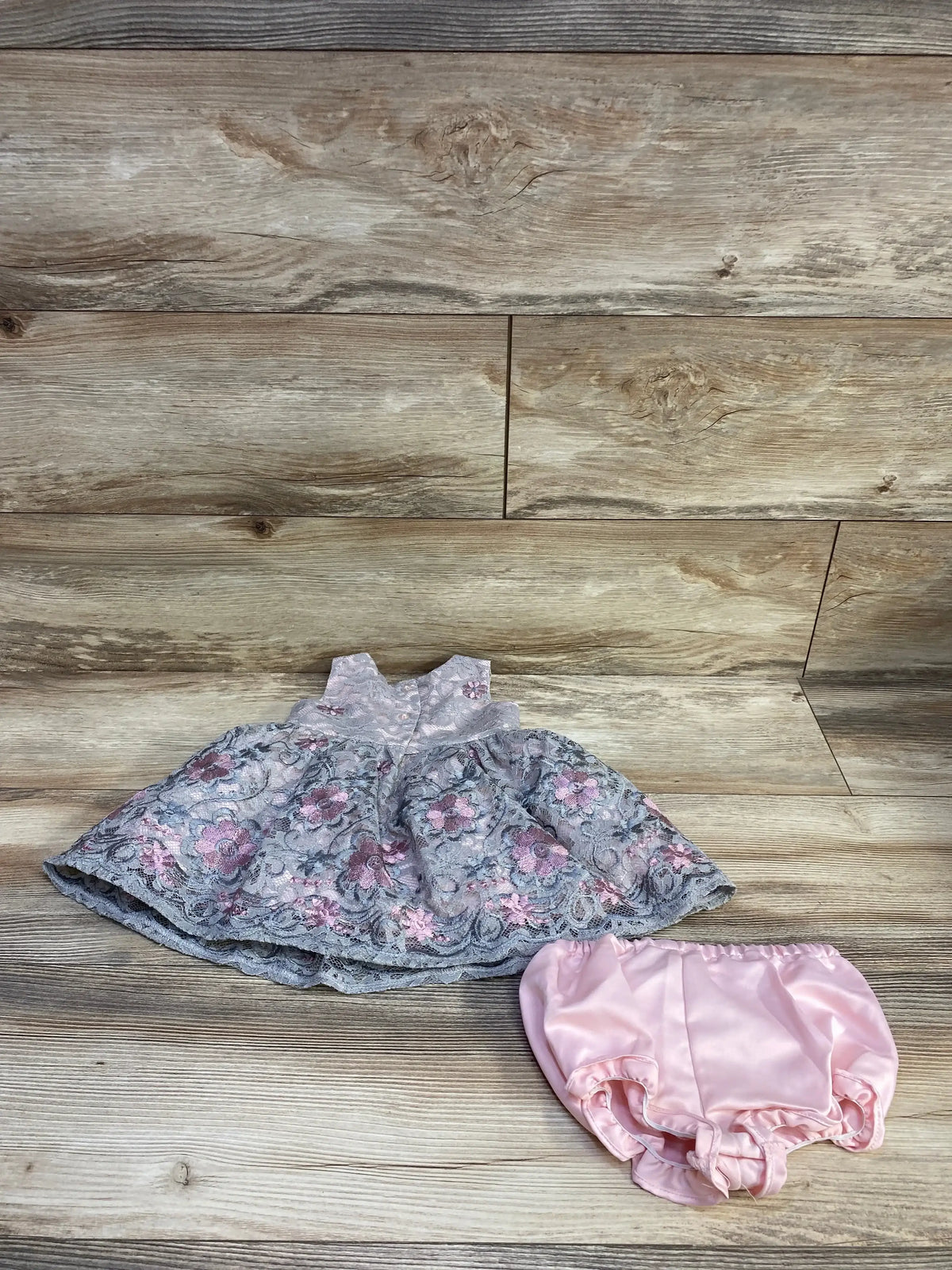 Overhead view of Laura Ashley lace floral dress and bloomers showcasing floral lace and sleeveless design on wood planks
