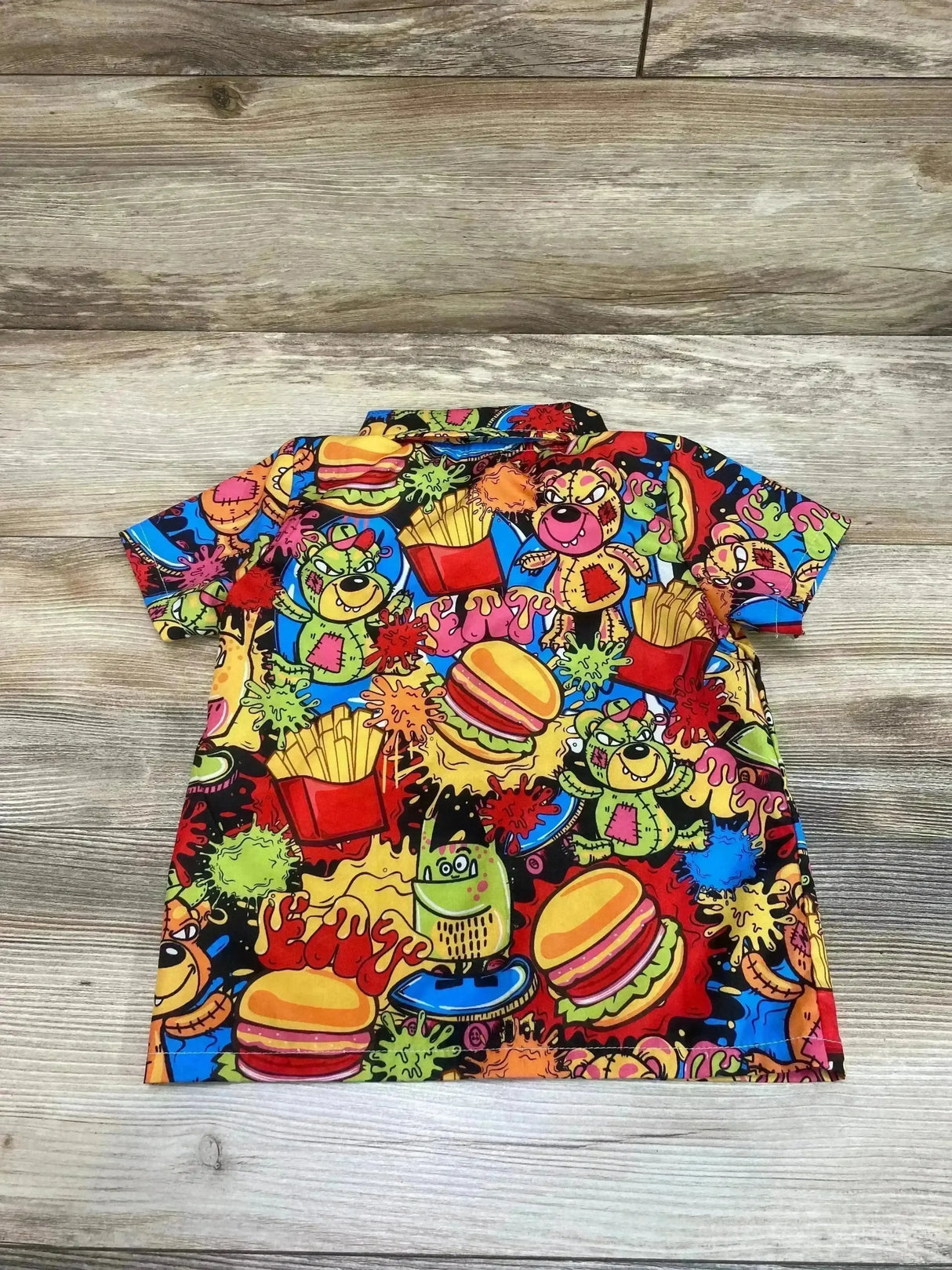 Flat lay of Shein Burgers and Fries Button Up Shirt sz 4Y showcasing colorful short sleeve shirt with monsters burgers and fries print on wood floor
