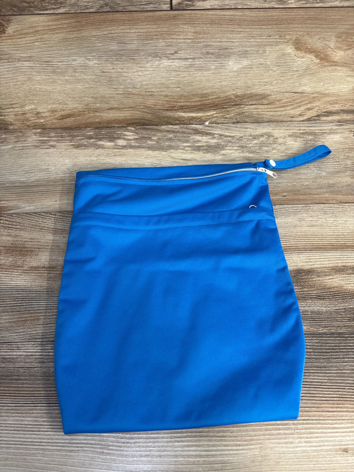 Blue reusable wet bag with zipper closure on wooden surface