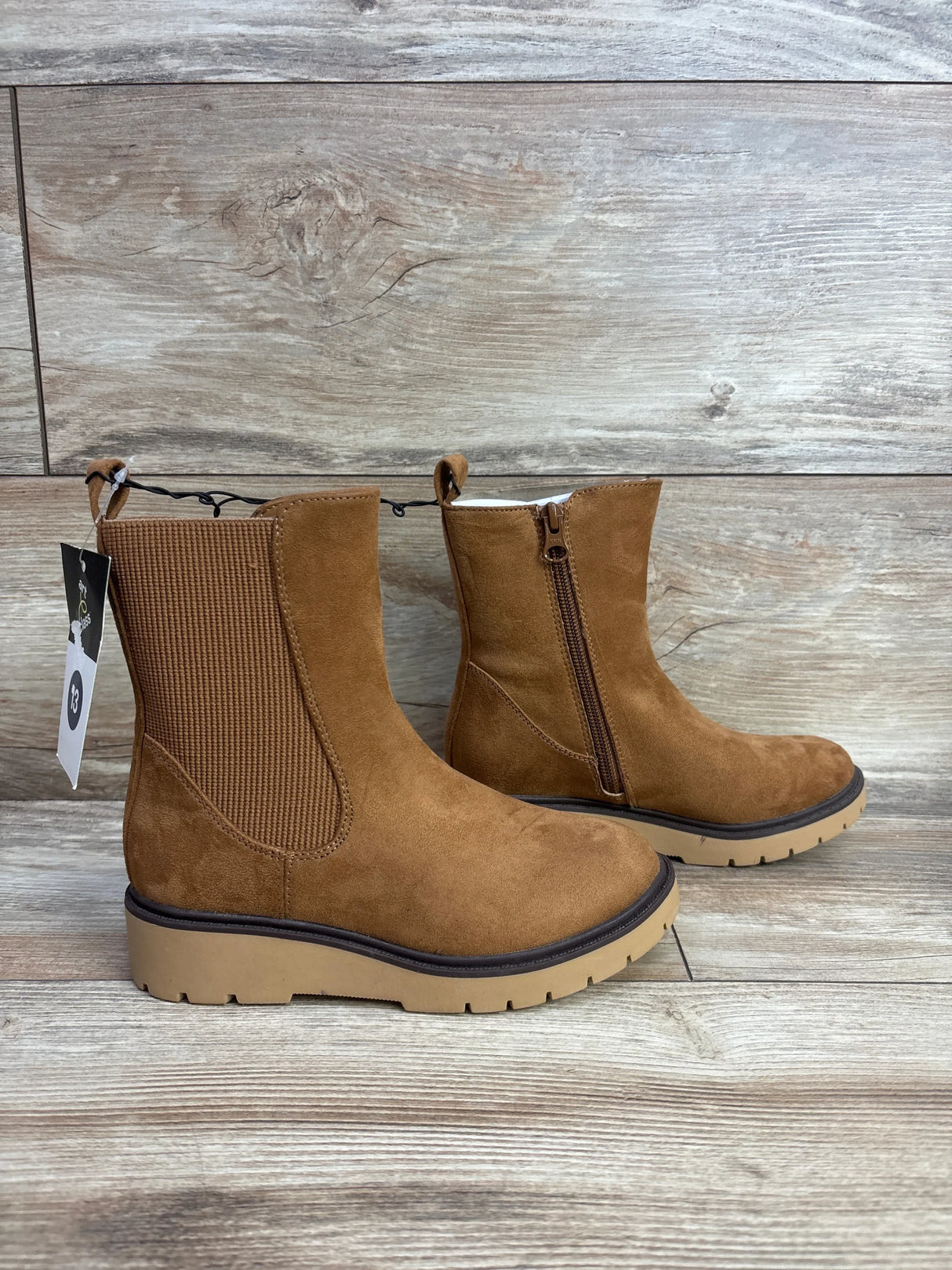 Kids brown suede ankle boots with zipper and ridged sole on wood floor