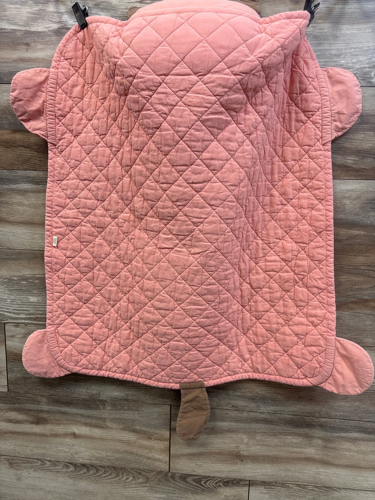 Top view of pink quilted cat toddler nap mat with ears, paws, and tail on a wood floor