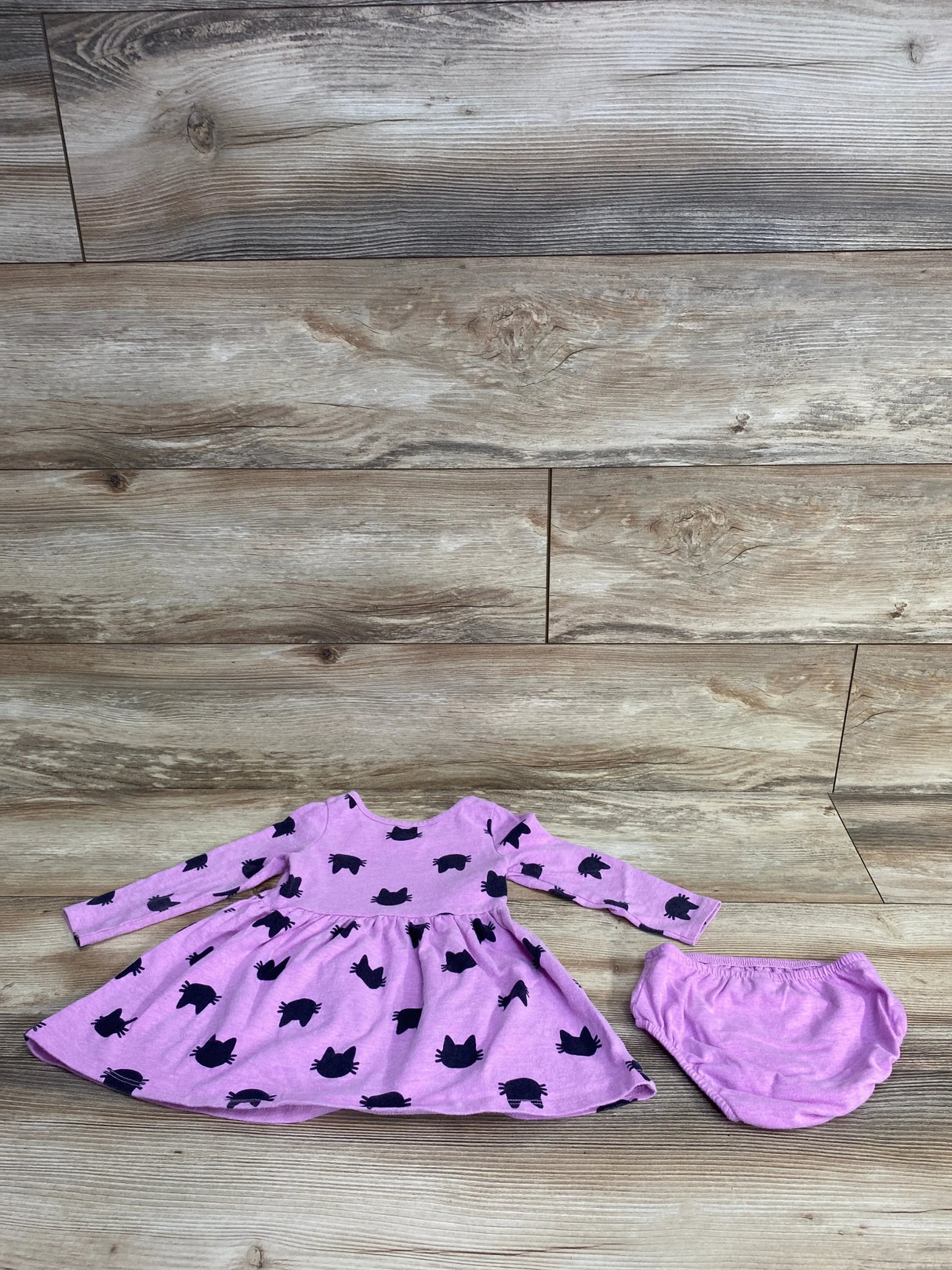 Front view of pink Cat & Jack long-sleeve toddler dress with black cat silhouettes and matching bloomers laid flat on wood floor