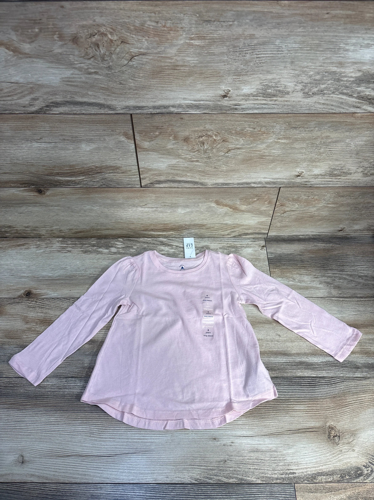 Light pink long sleeve toddler shirt by baby GAP on wooden floor background