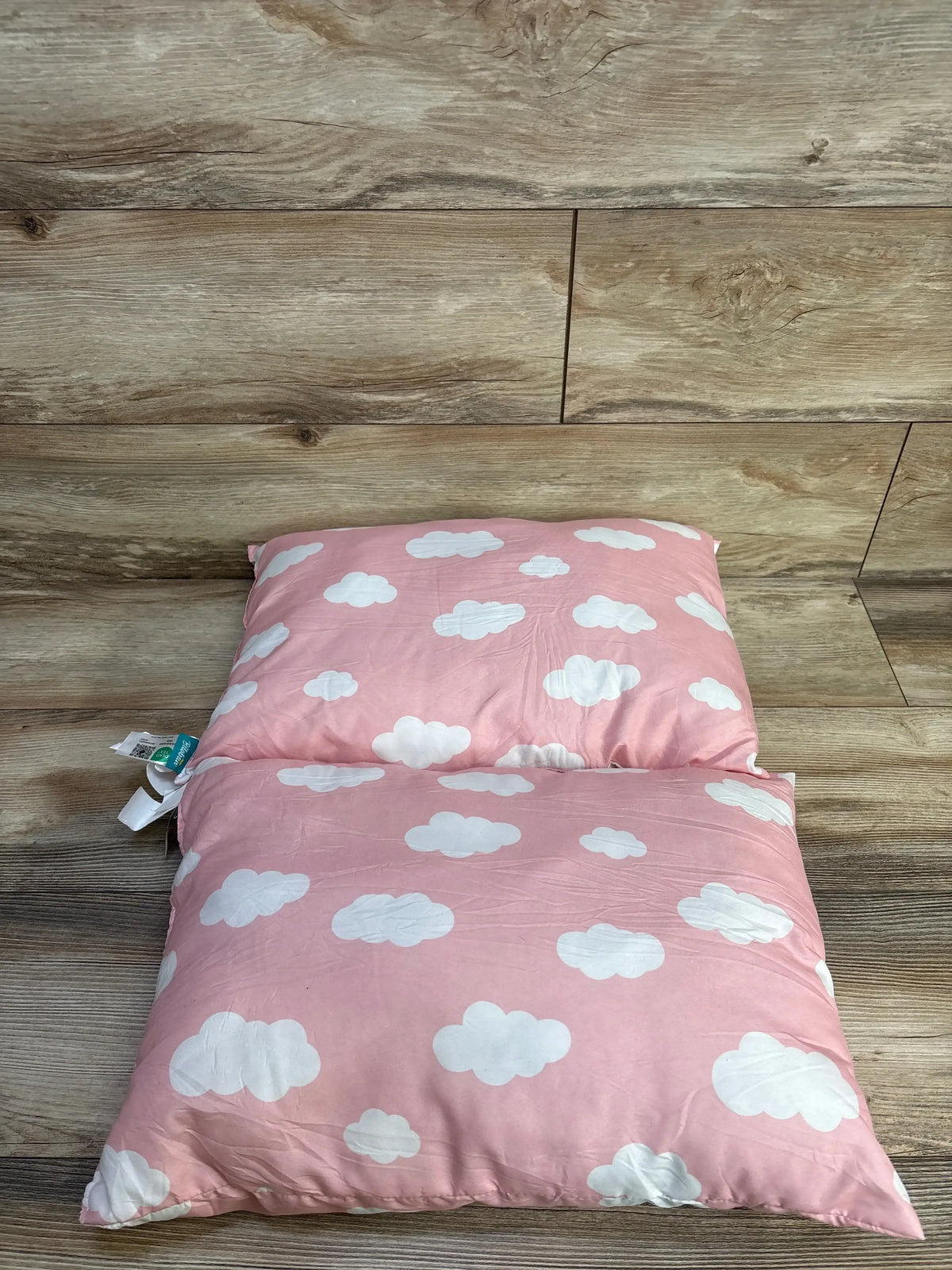 Top view of two Biloban toddler pillows showcasing pink fabric with white cloud pattern on wood-look flooring