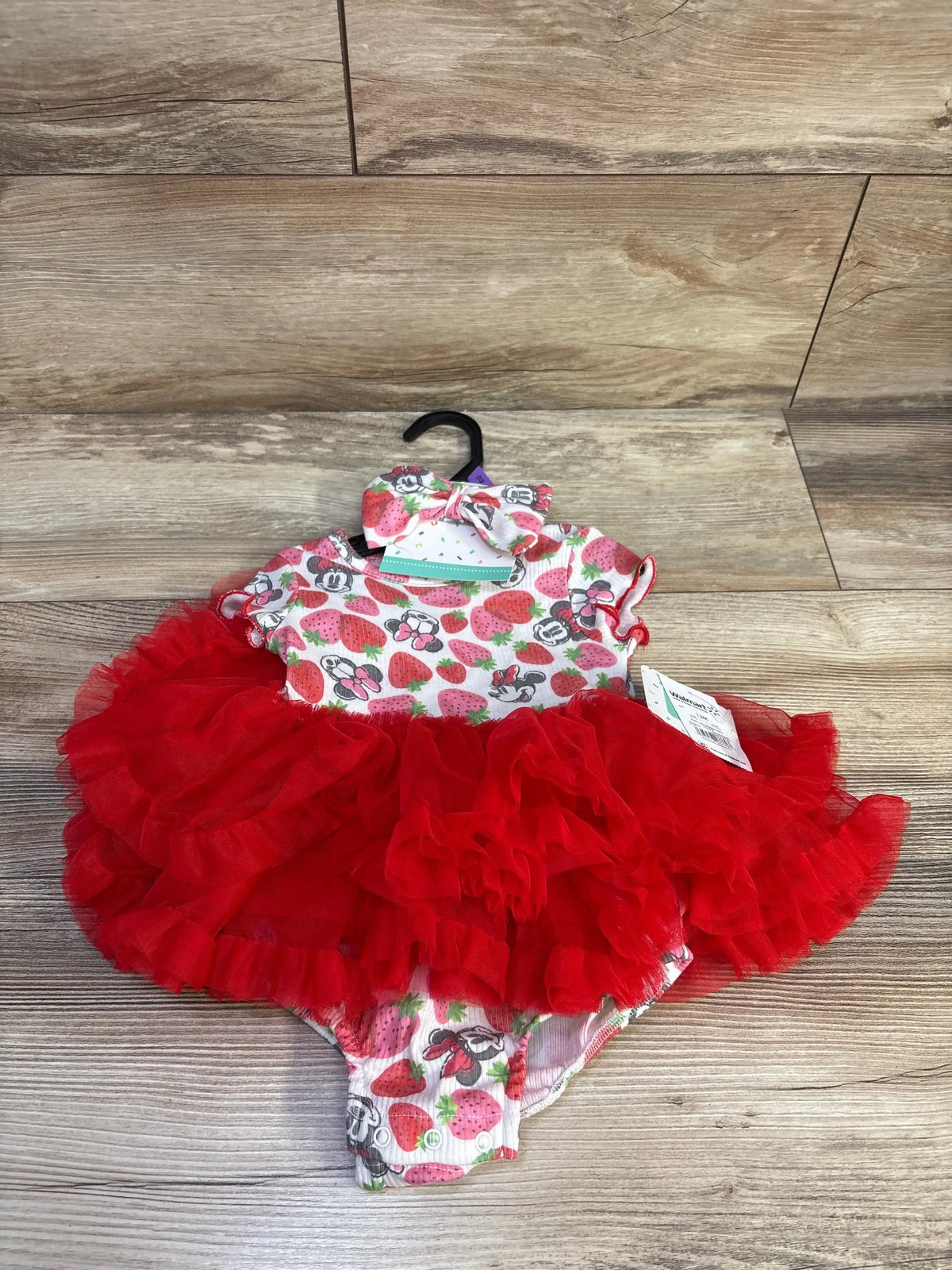 Front view of Disney Baby Minnie Mouse 2-piece bodysuit with red tulle tutu and matching bow headband on wood floor