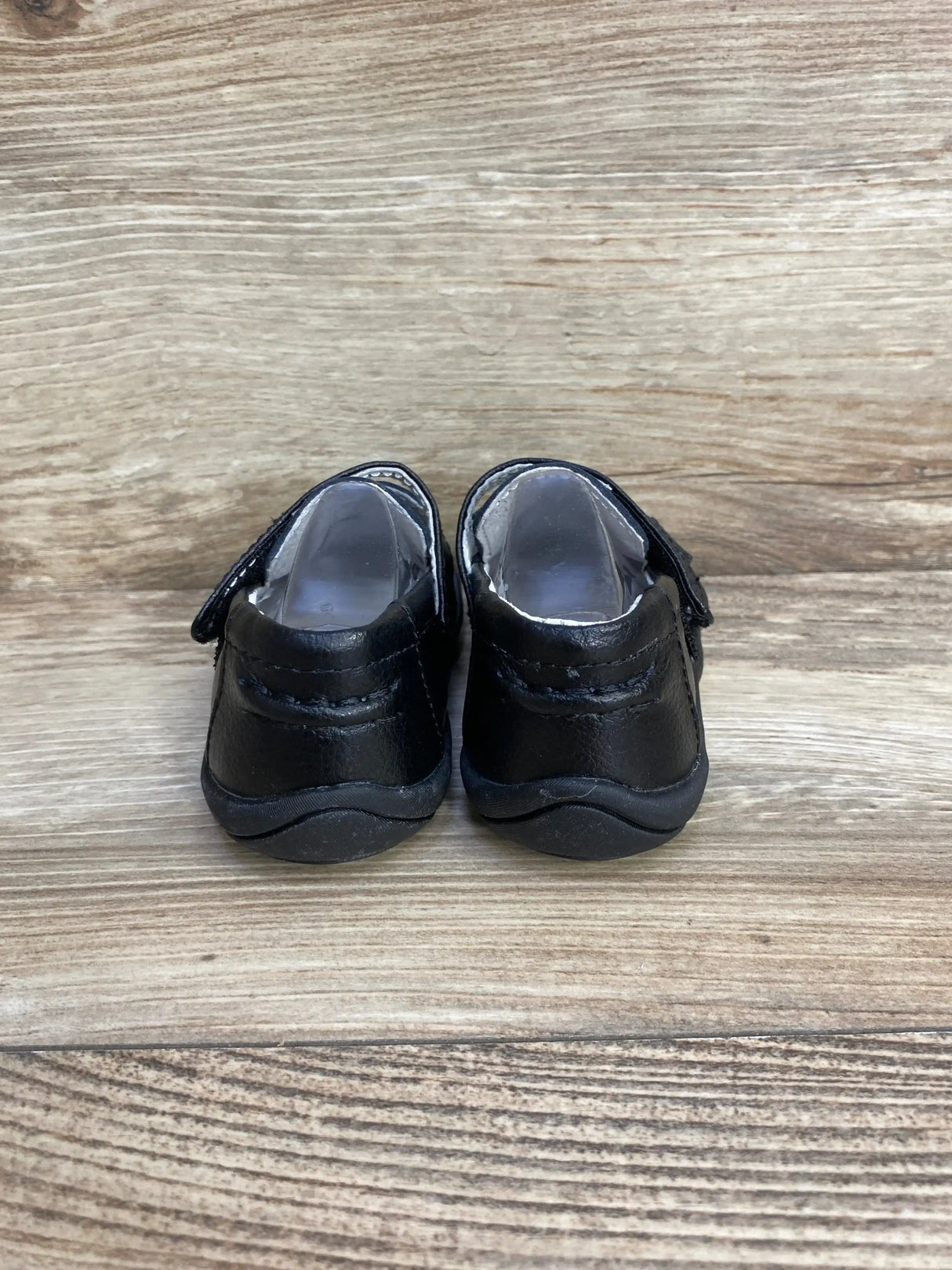 Rear view of Pediped Charlie toddler loafers in black showing stitched leather heel and rubber sole on wood background