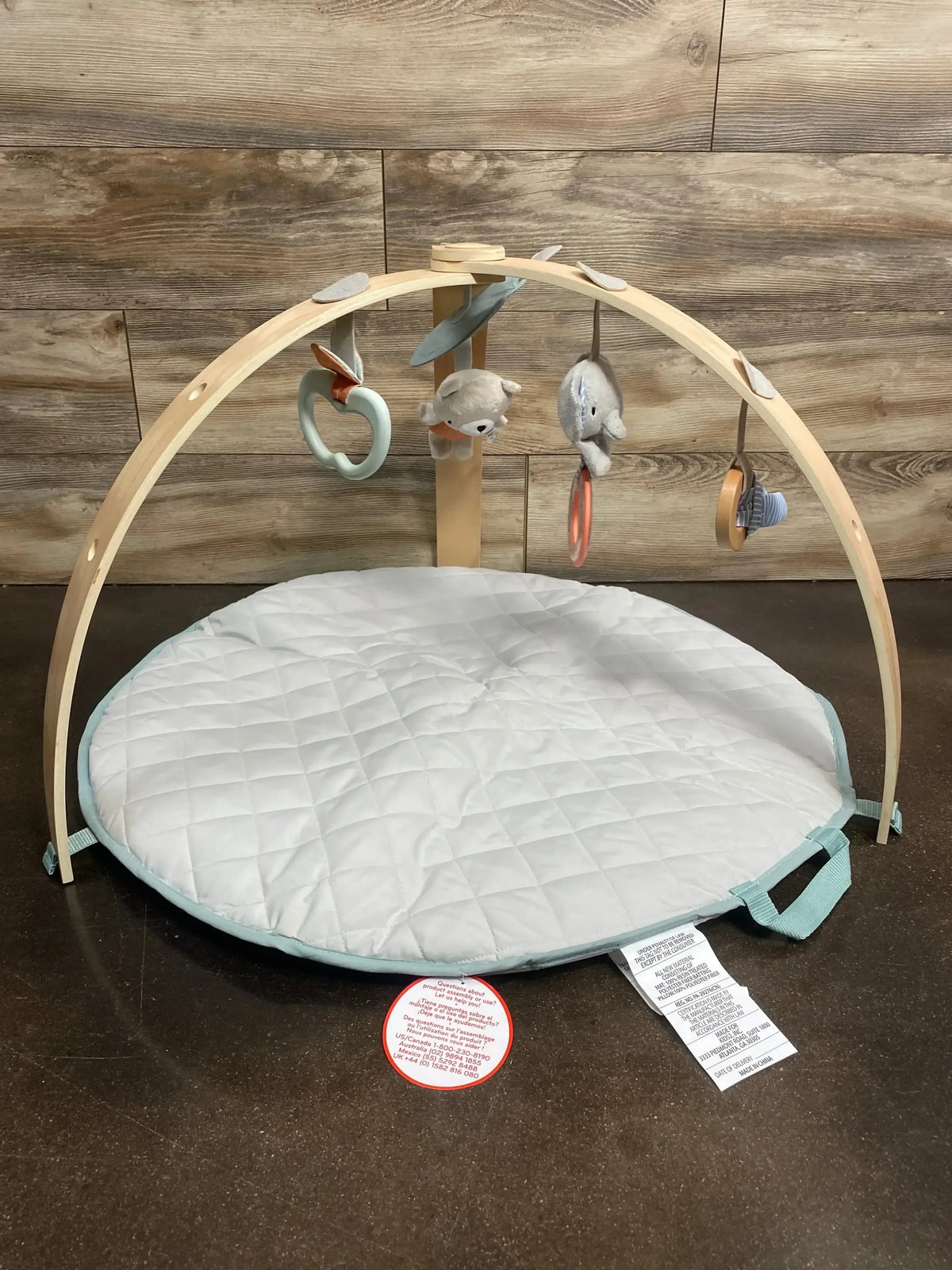 Front view of Ingenuity Cozy Spot reversible duvet activity gym with quilted mat, wooden arches and hanging activity toys
