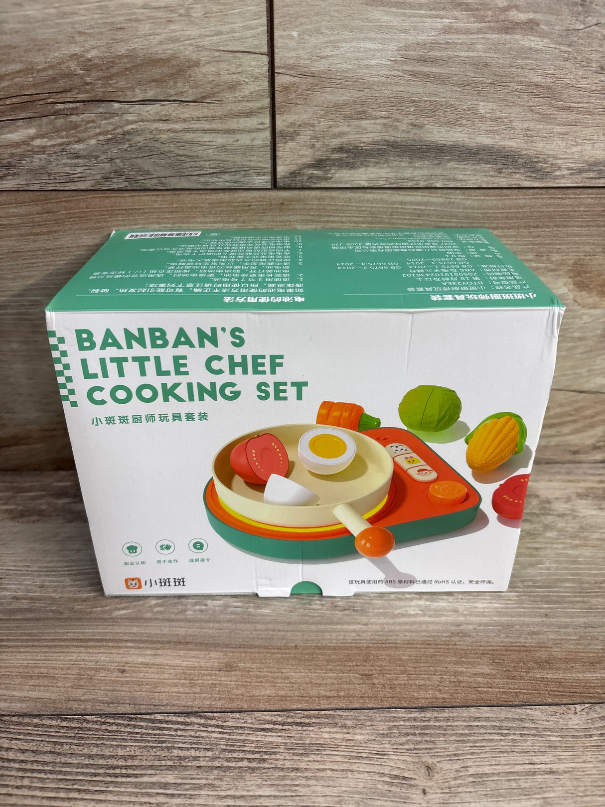 Banban's Little Chef Cooking Set toy box with play pan, vegetables, and stove on wooden surface