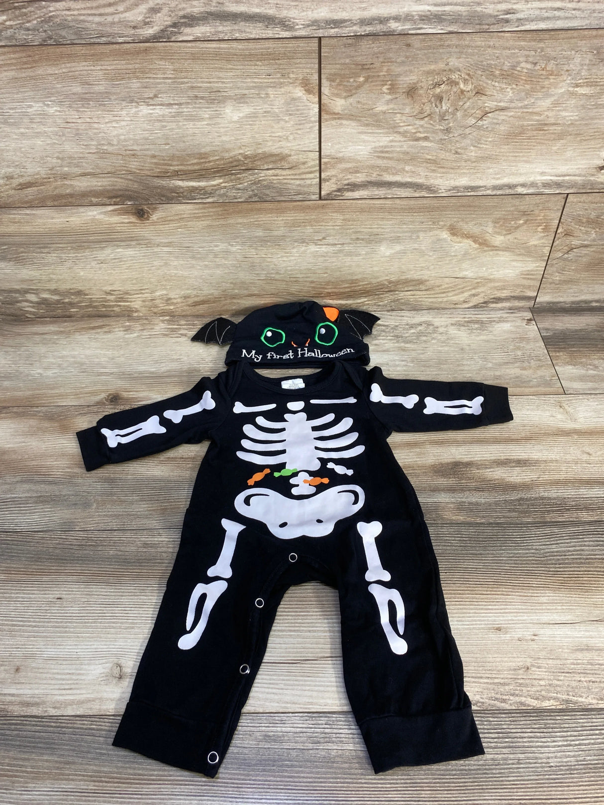 Baby skeleton Halloween costume with 'My first Halloween' bat hat, black long-sleeve onesie, white bones, candy print