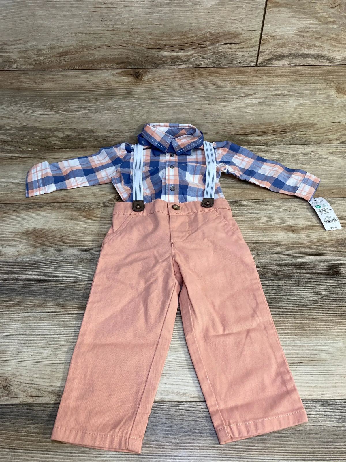 Flat-lay of 4-piece plaid button-up suspender set showcasing blue-and-peach plaid shirt with white-striped suspenders and peach pants on wood background