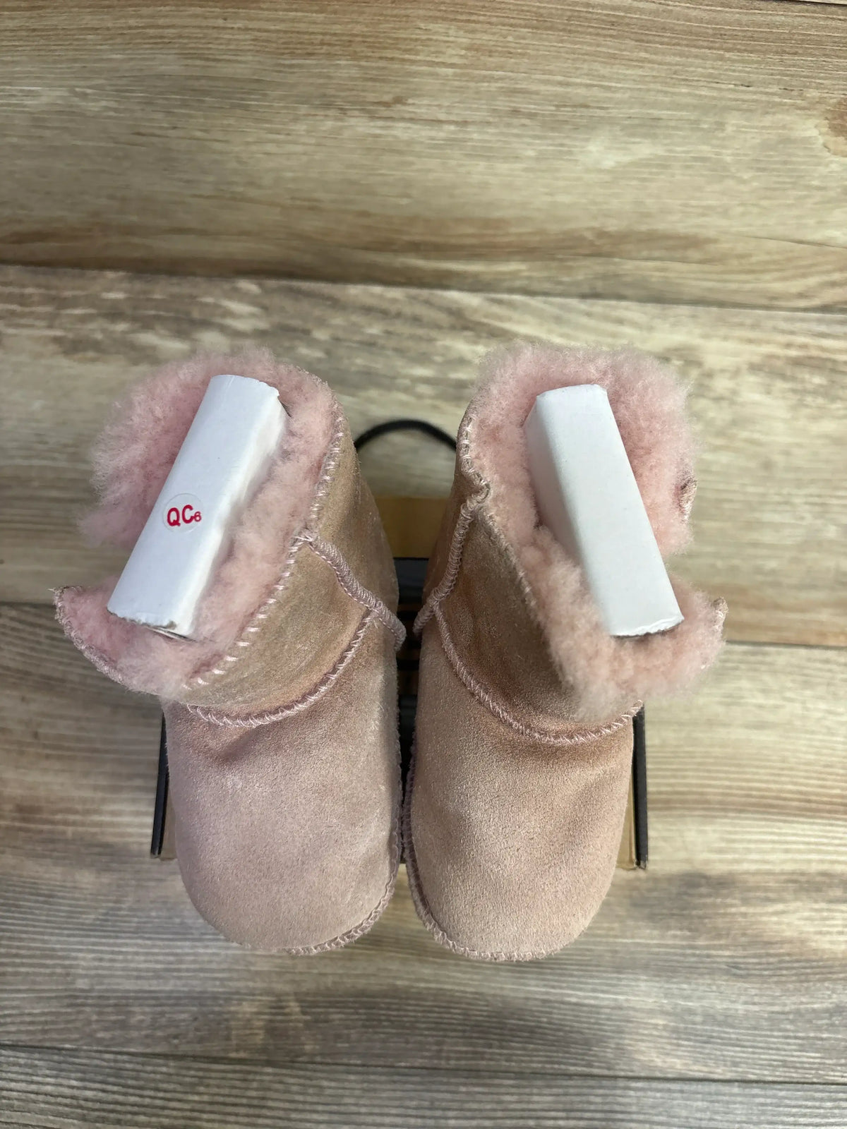 Top-down view of UGG Australia Erin booties in soft pink showing suede exterior and plush sheepskin lining on wooden surface