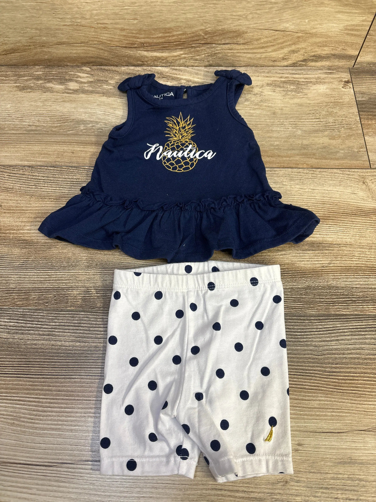 Front view of Nautica navy peplum top and leggings set with shoulder bows, ruffled hem, pineapple graphic, and polka dots